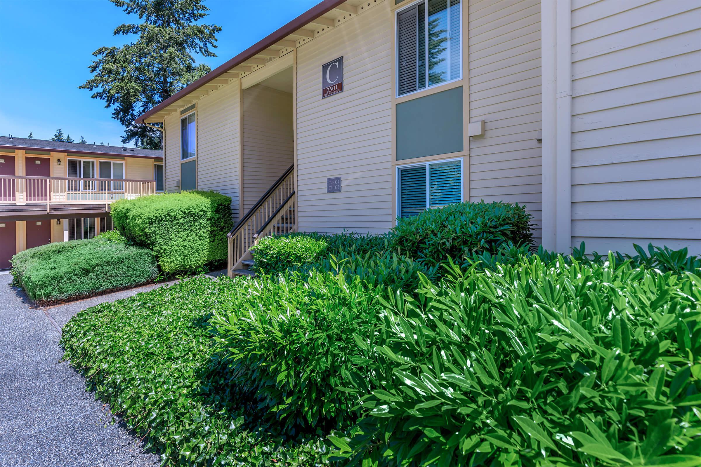 a house with bushes in front of a brick building