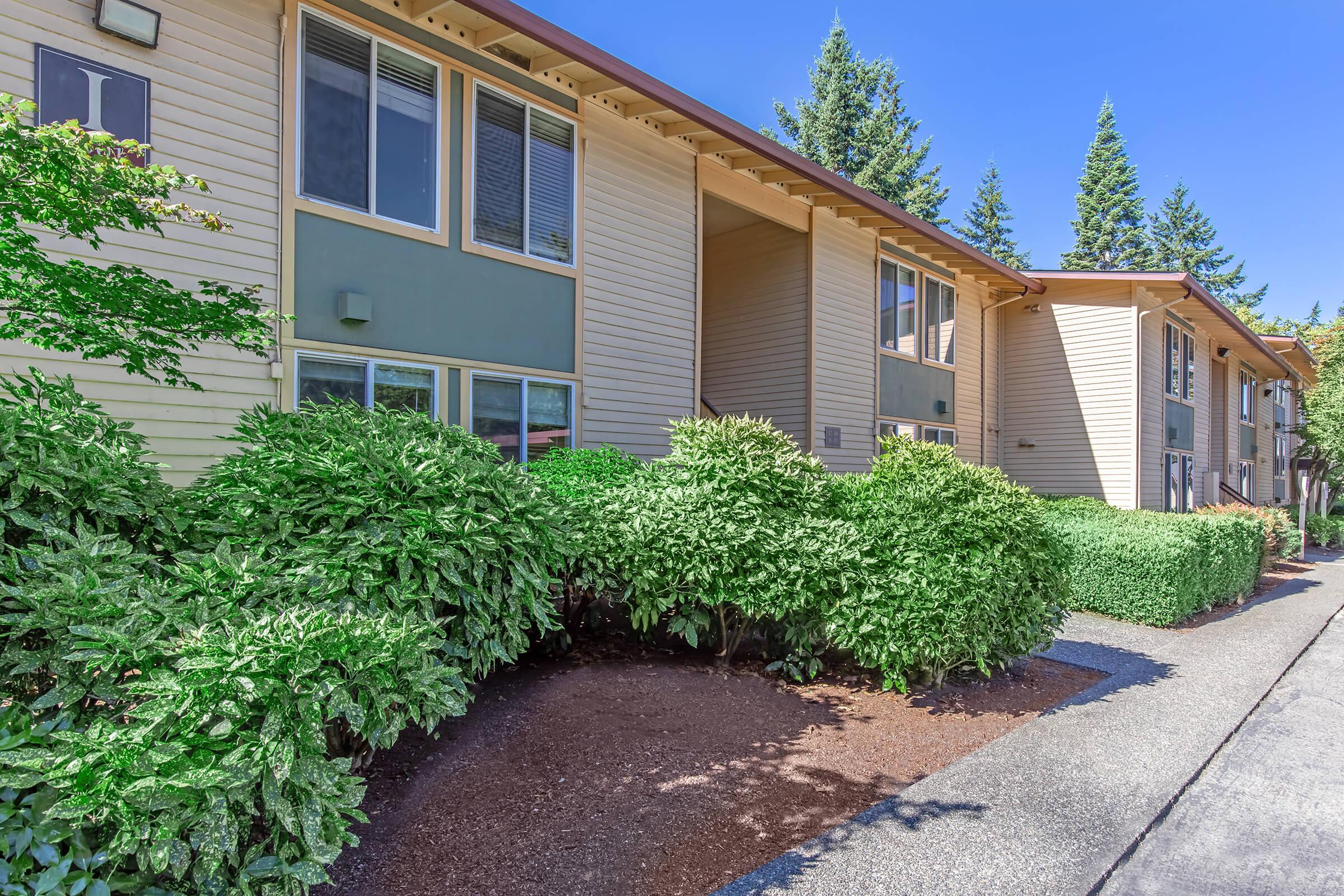 a house with bushes in front of a brick building