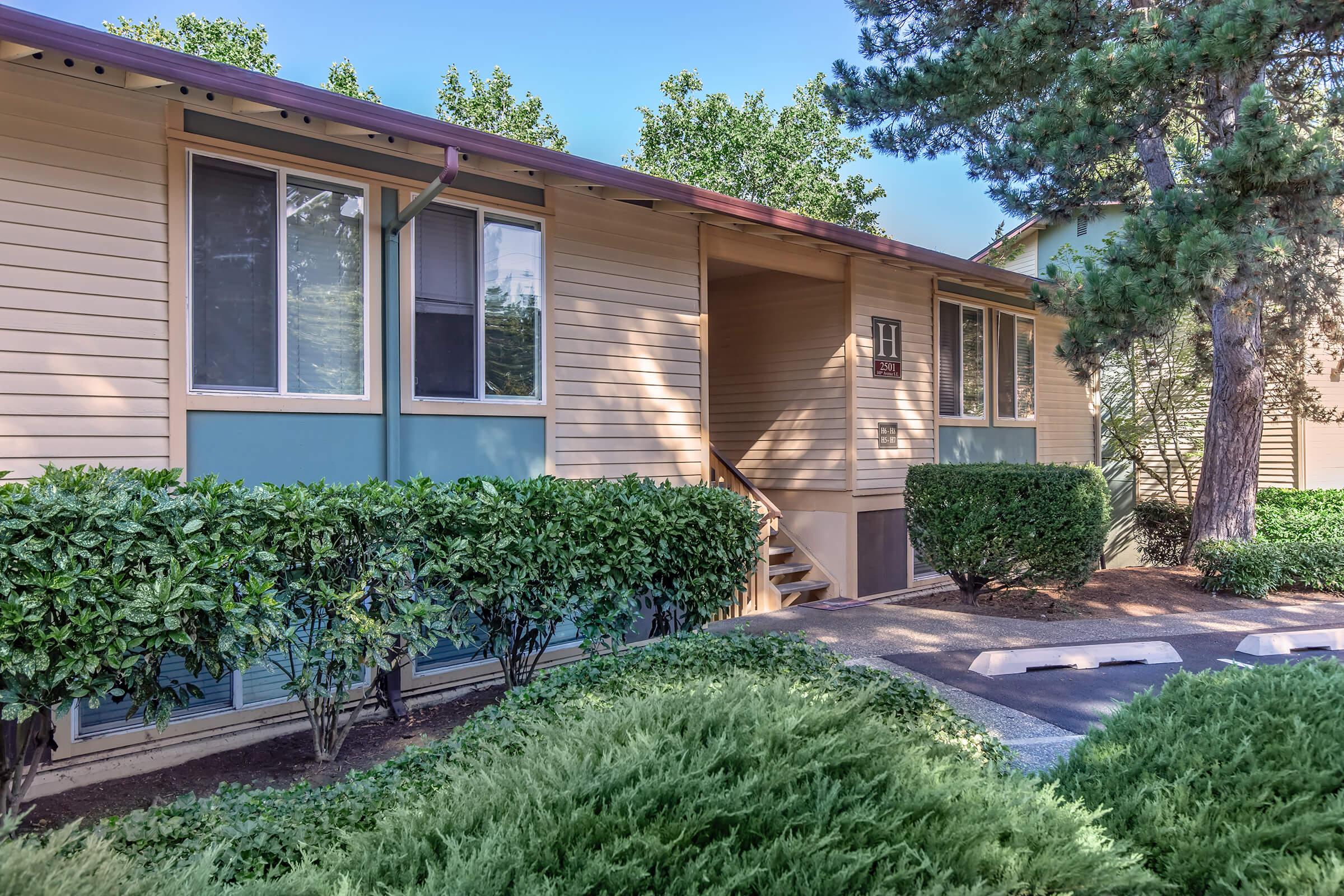 a house with bushes in front of a brick building