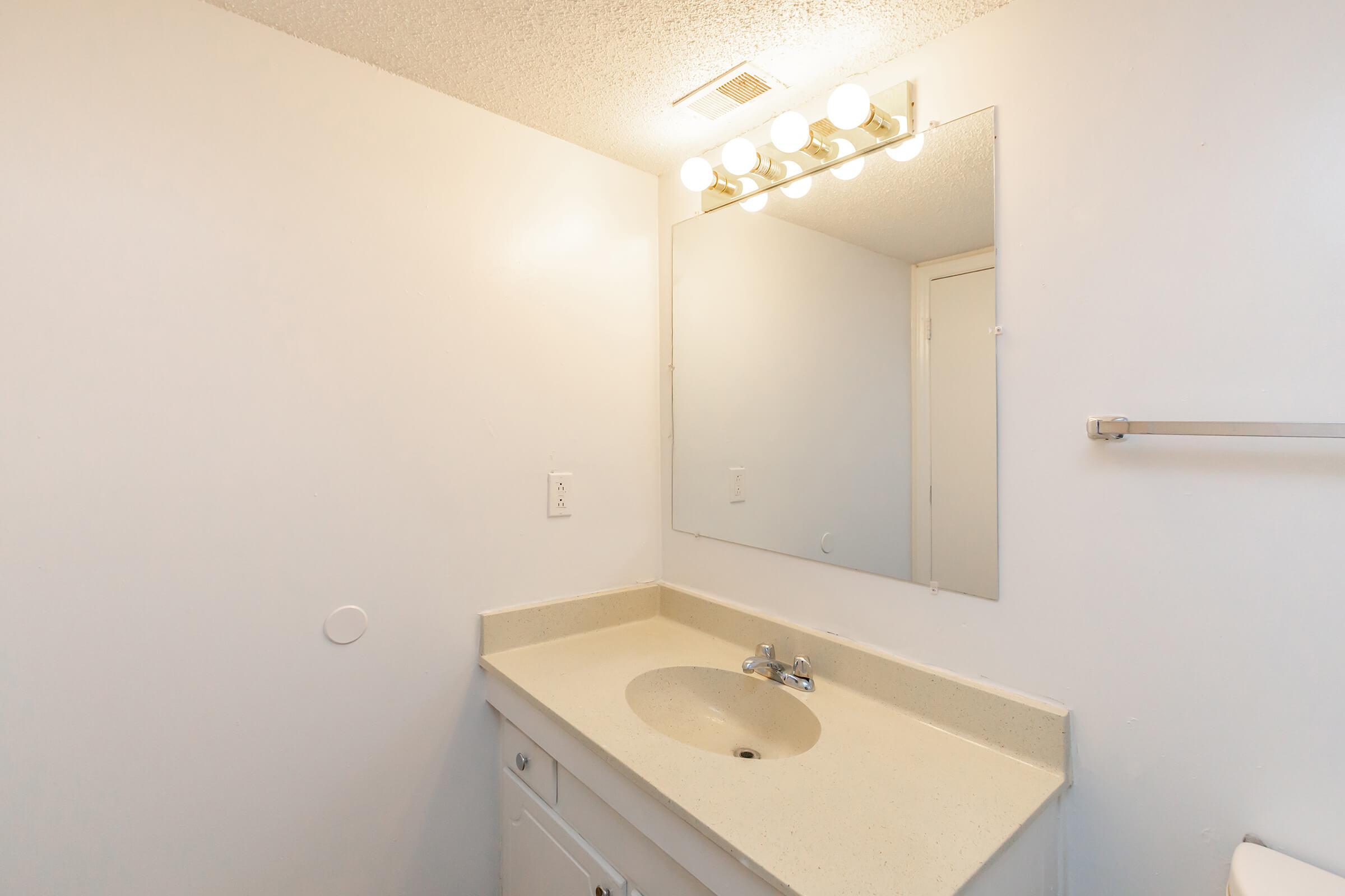 a white sink sitting under a mirror