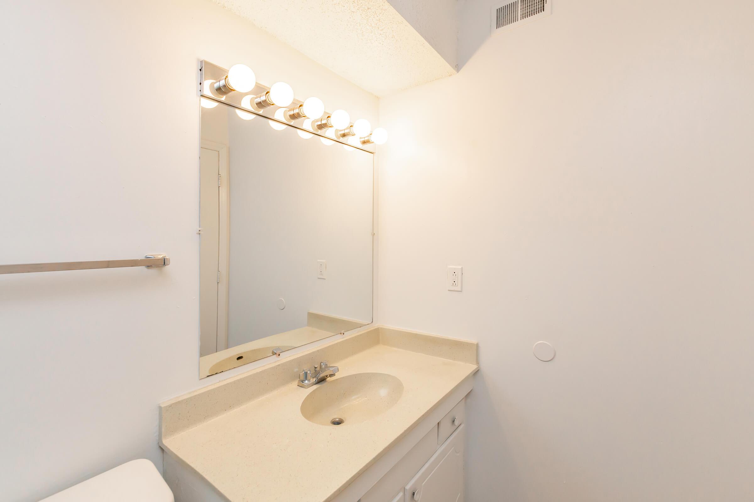 a white sink sitting under a mirror