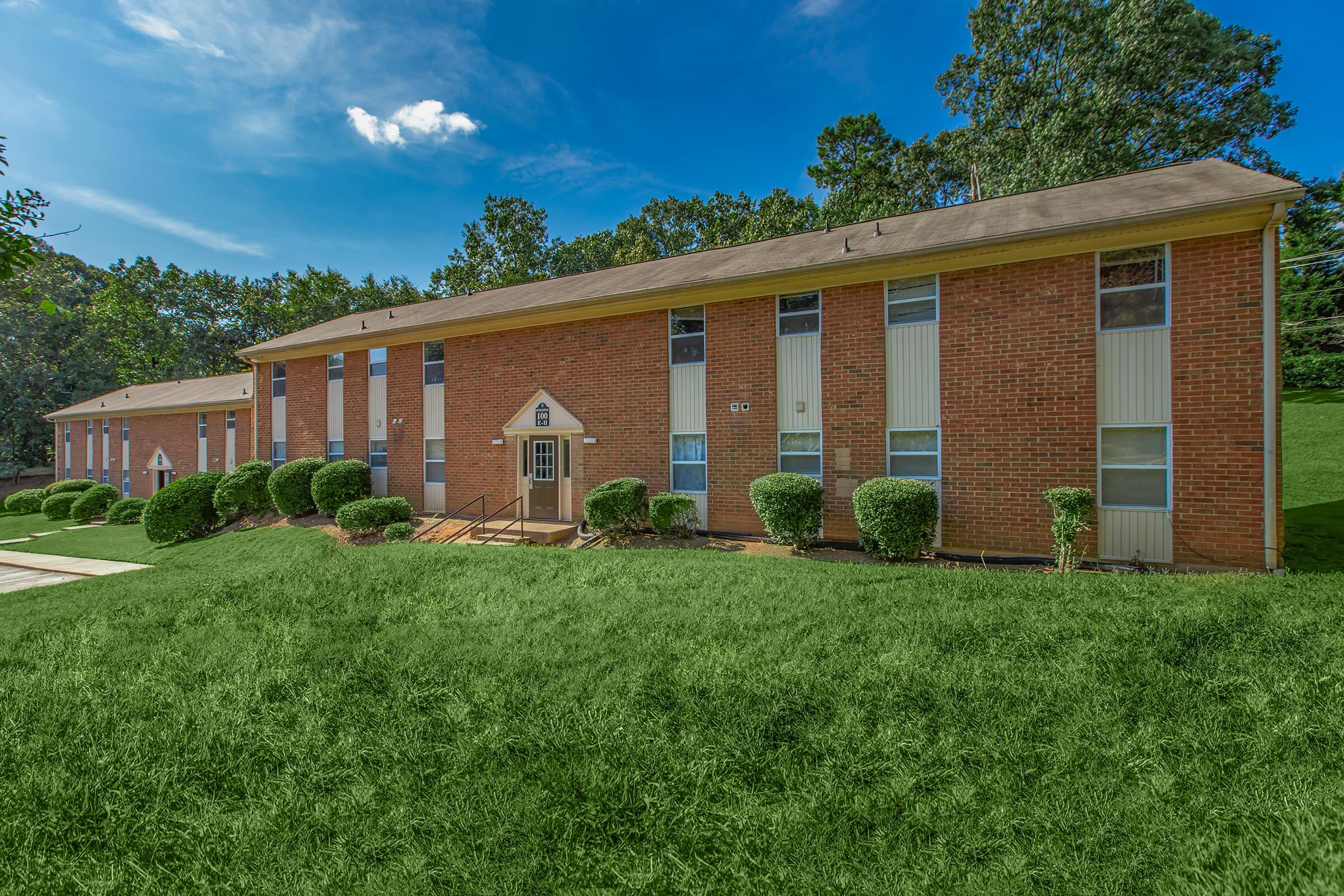 a large brick building with grass in front of a house