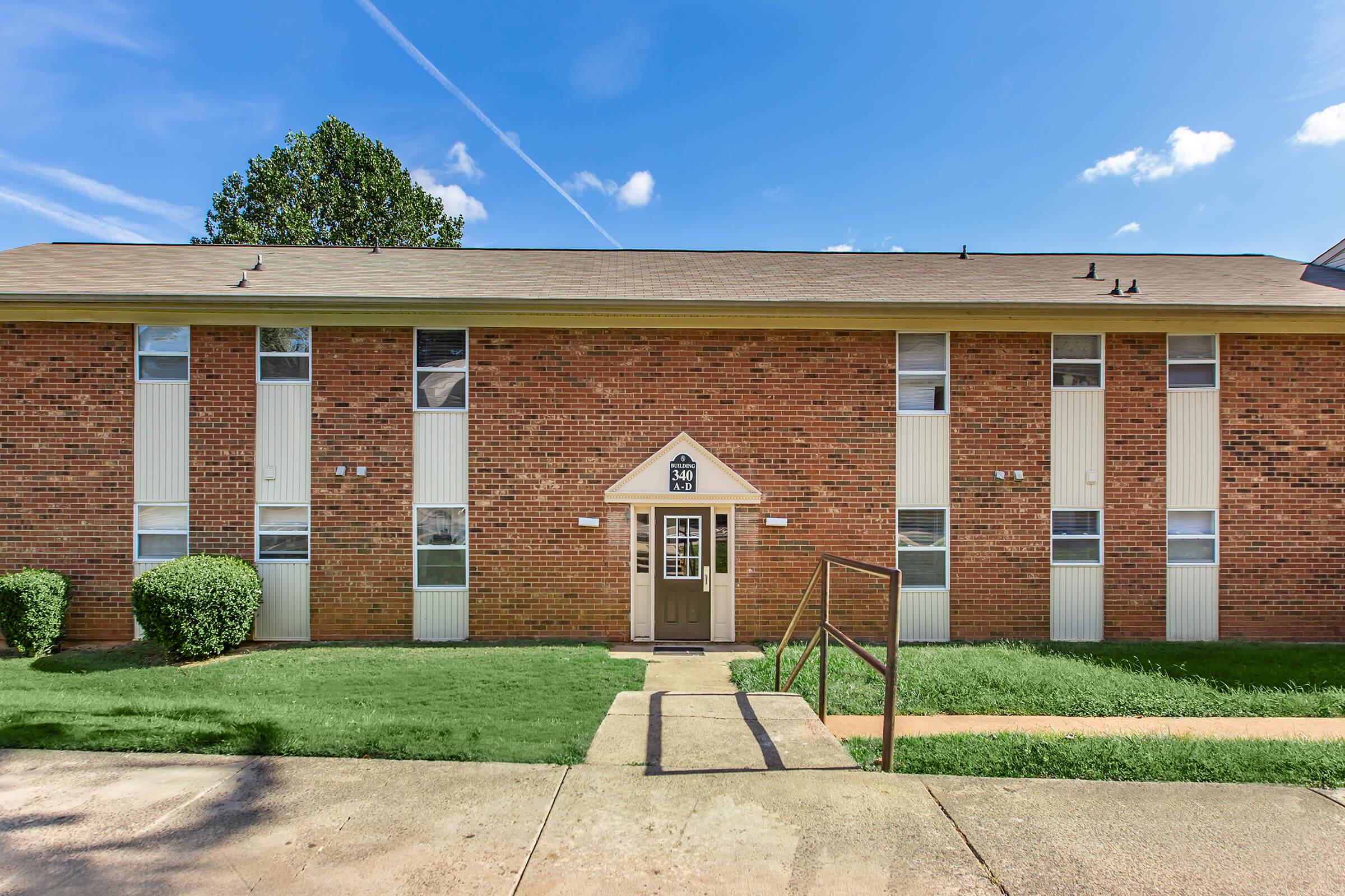 a large brick building with grass in front of a house