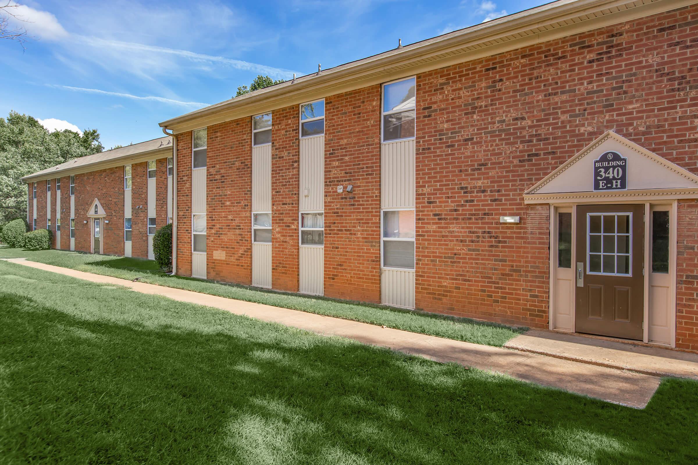 a large brick building with grass in front of a house