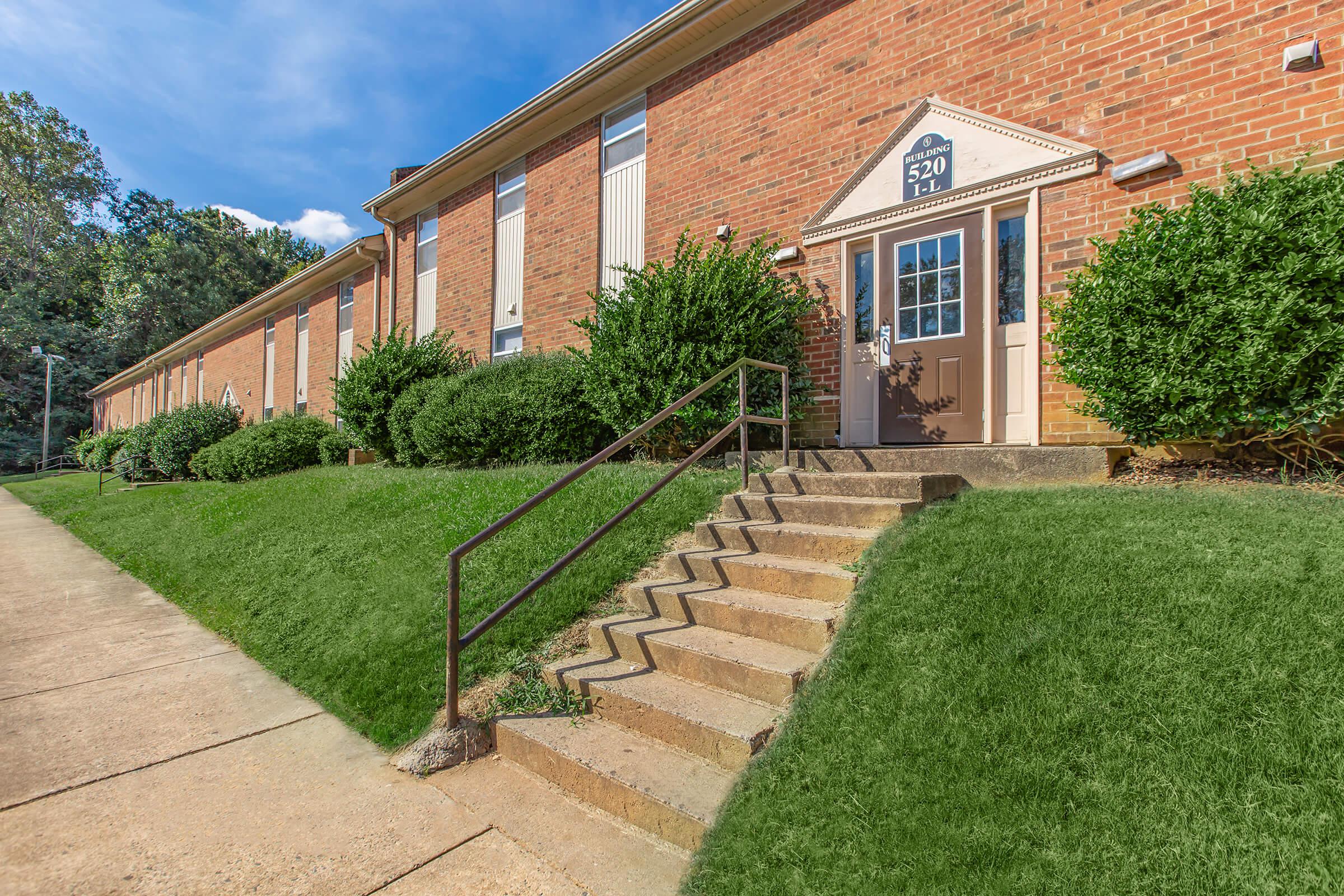 a large brick building with grass in front of a house