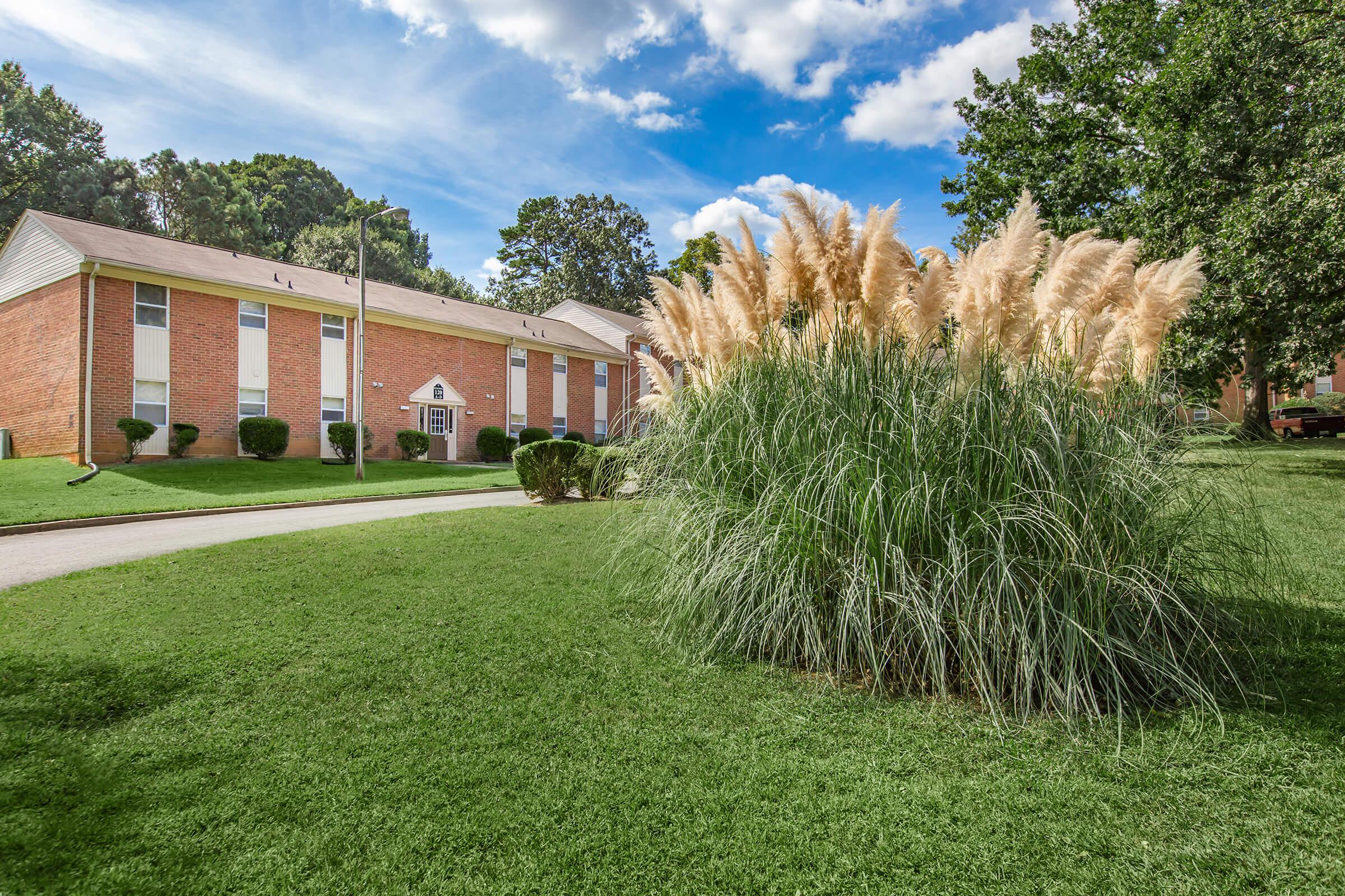 a large brick building with a grassy field