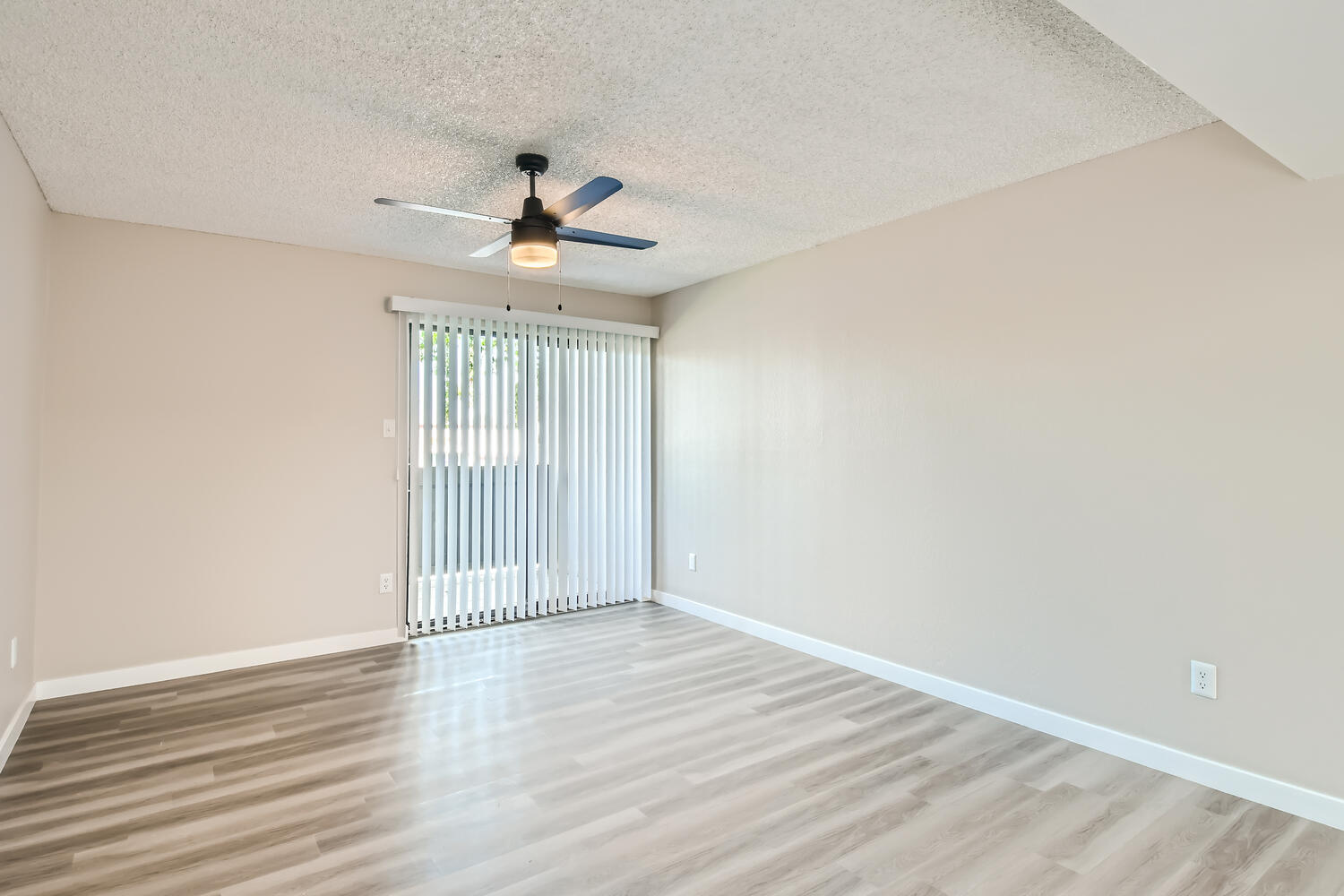 An apartment living room with sliding glass doors leading to the balcony at Rise on MClintock.