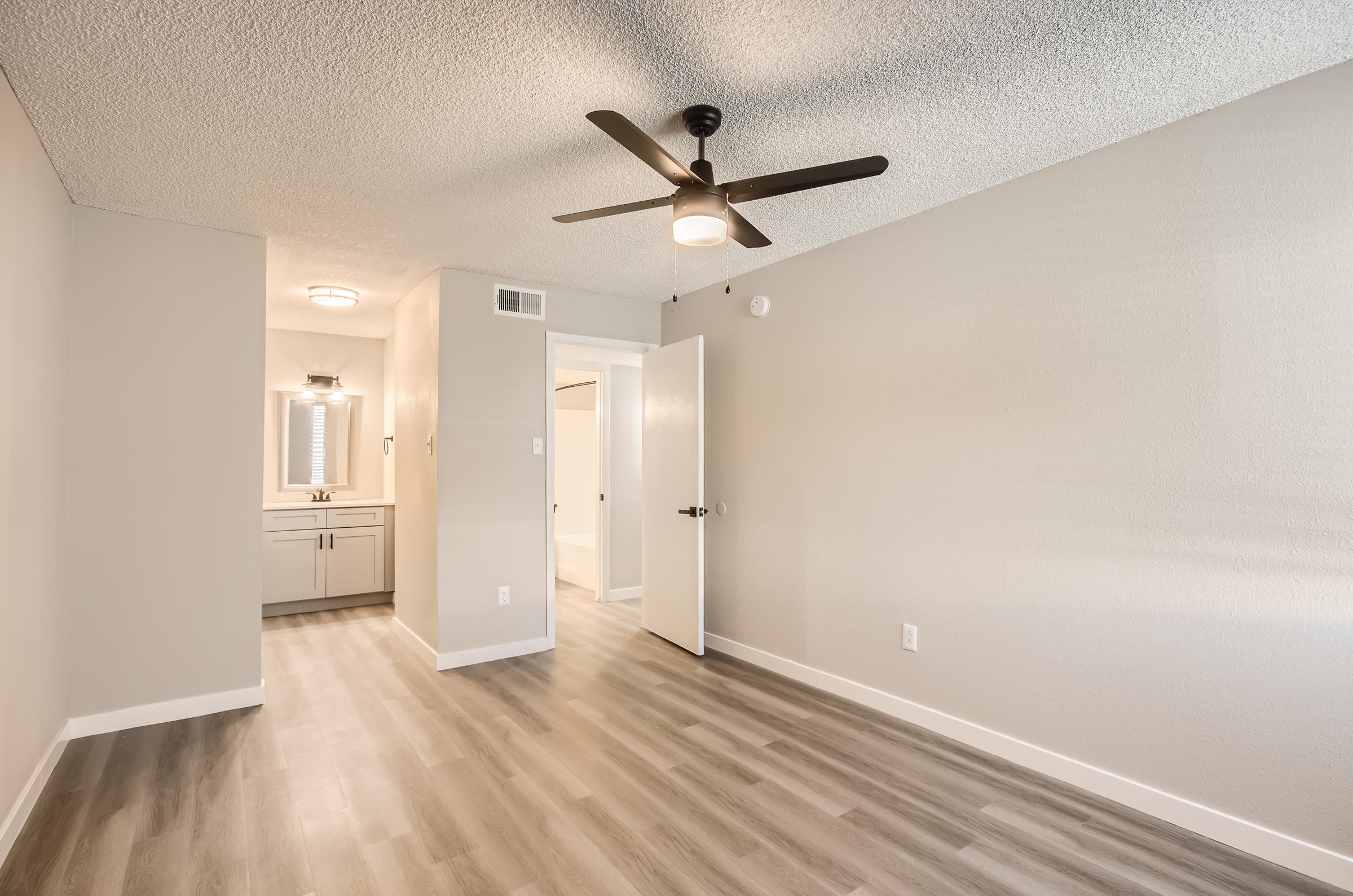 A bedroom with wood-style flooring and a ceiling fan at Rise on McClintock.