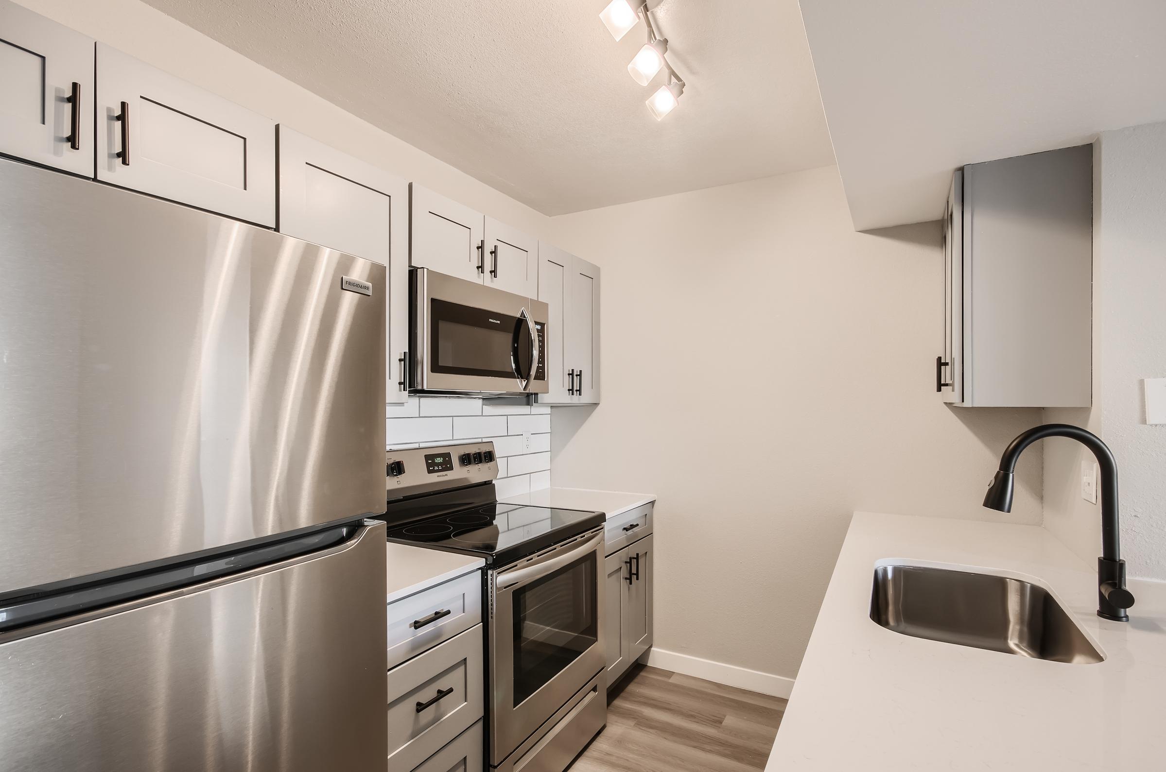 A remodeled galley kitchen with white cabinets and stainless steel appliances at Rise on McClintock.