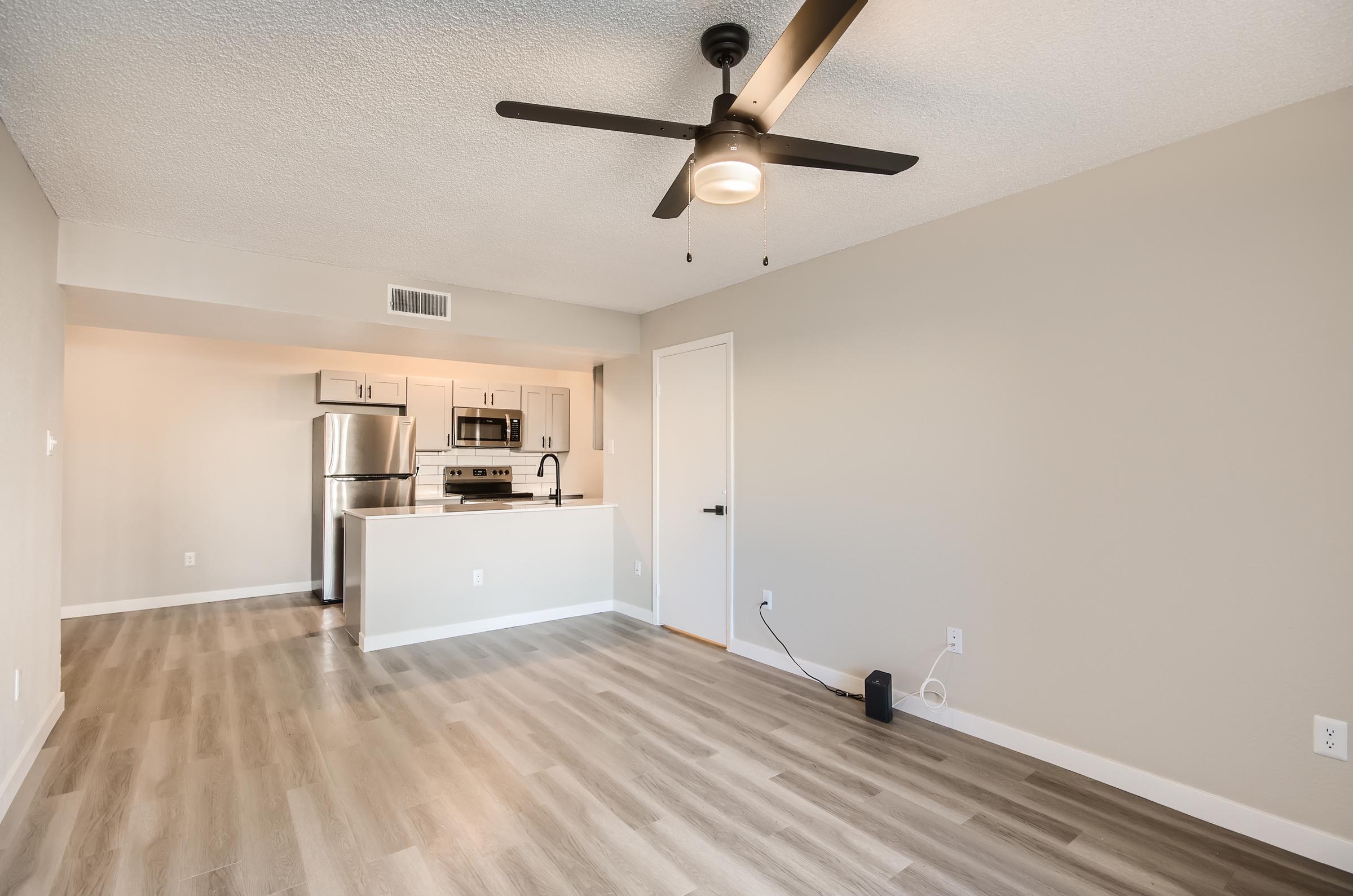 The open concept living space with wood-style floors and a kitchen at Rise on McClintock.