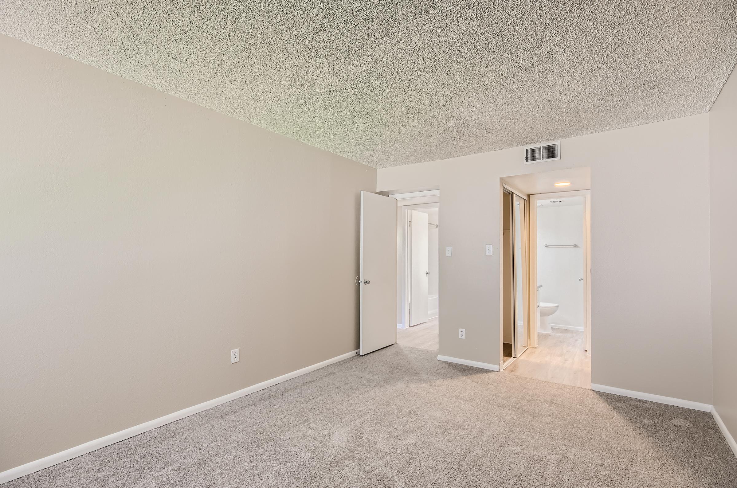 A carpeted bedroom near the kitchen with an en-suite bathroom at Rise on McClintock.
