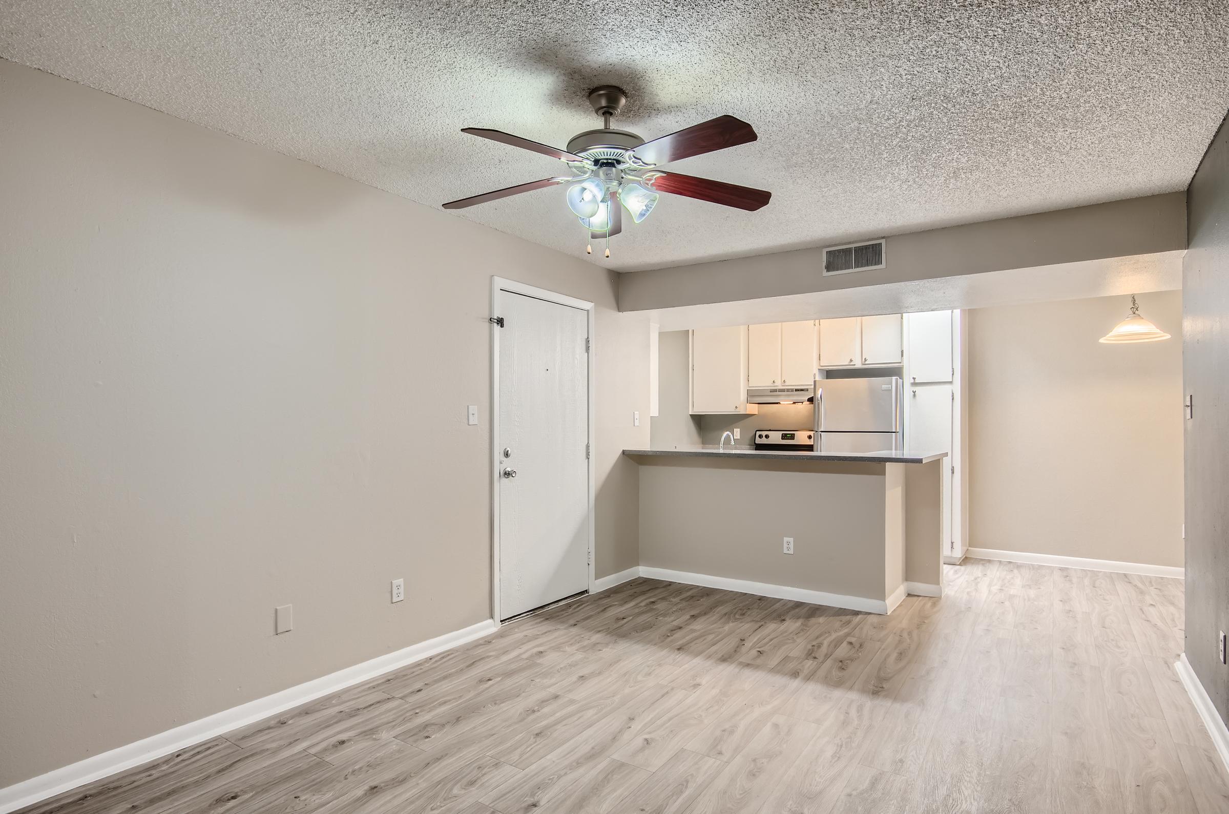 An open-concept apartment at Rise at McClintock with wood-style flooring, a ceiling fan, and a open kitchen.