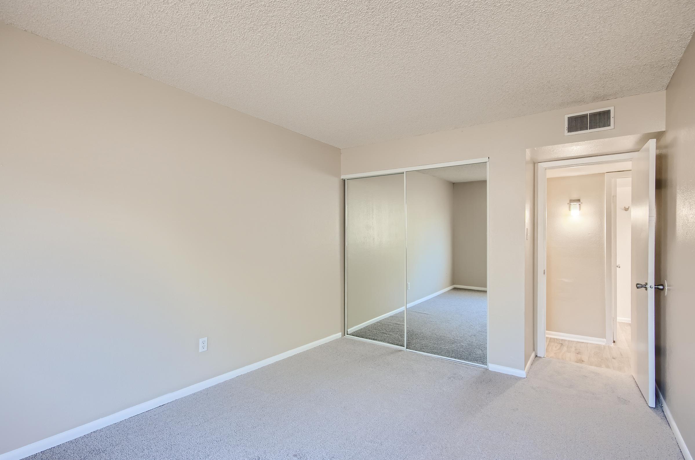 Carpeted bedroom at Rise on McClintock with a mirrored closet.