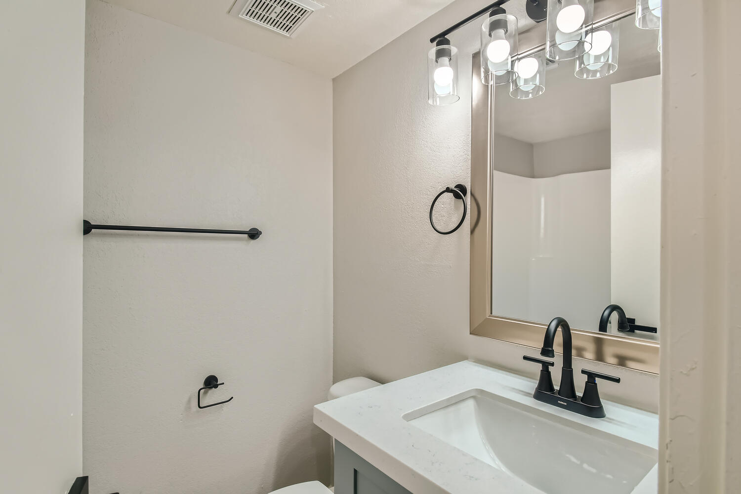 An apartment bathroom with a small vanity, a mirror and a toilet at Rise on McClintock.