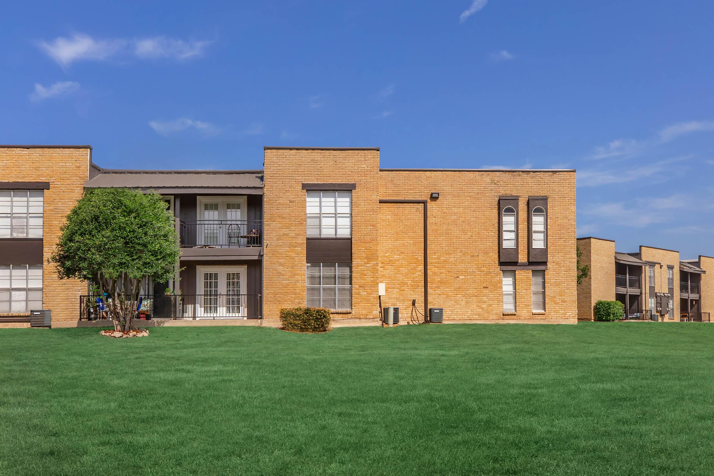 a large brick building with a grassy field