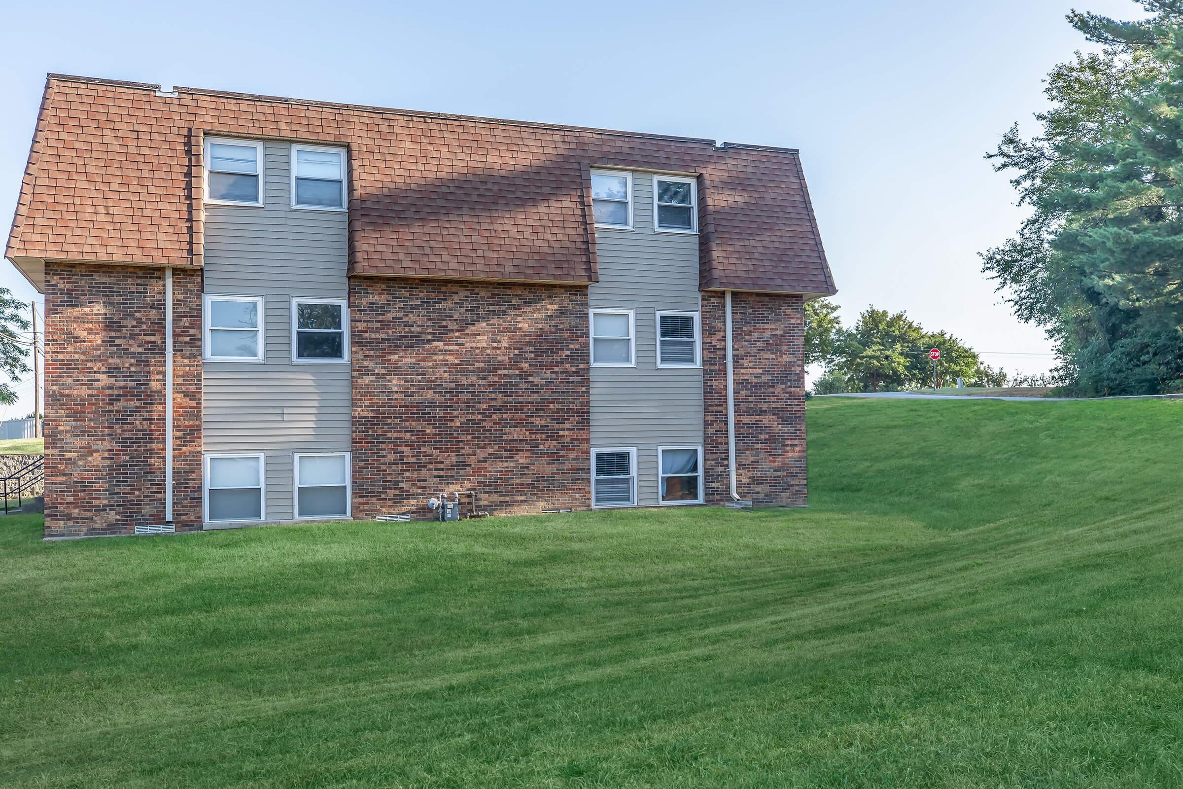 a large brick building with grass in front of a house