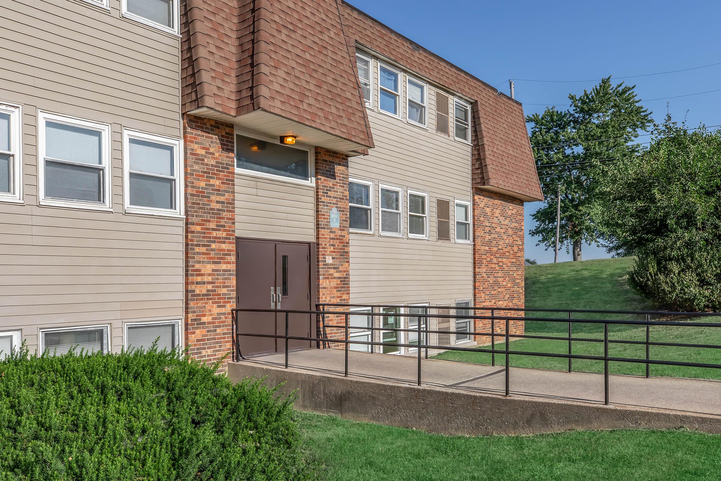 a large brick building with grass in front of a house