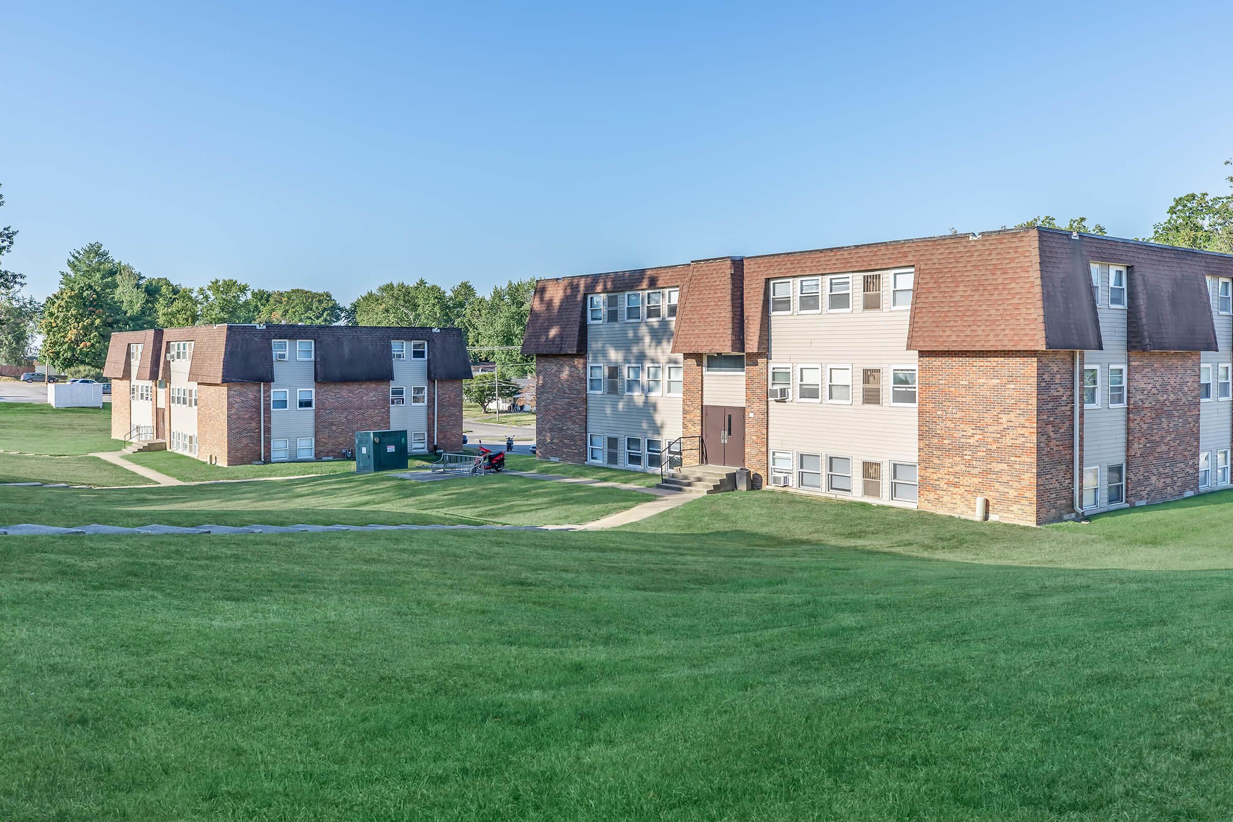 a large brick building with a grassy field