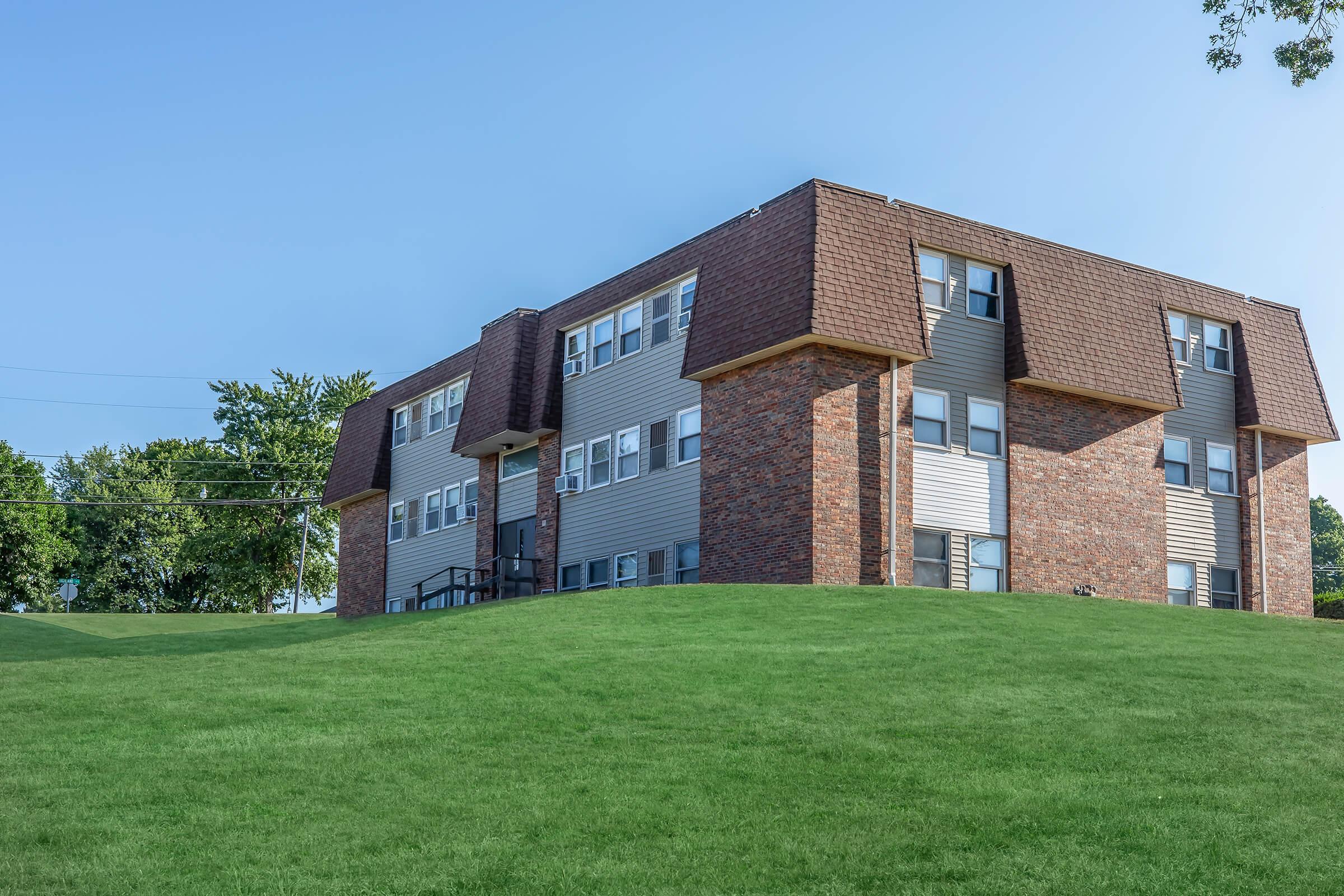 a large brick building with green grass