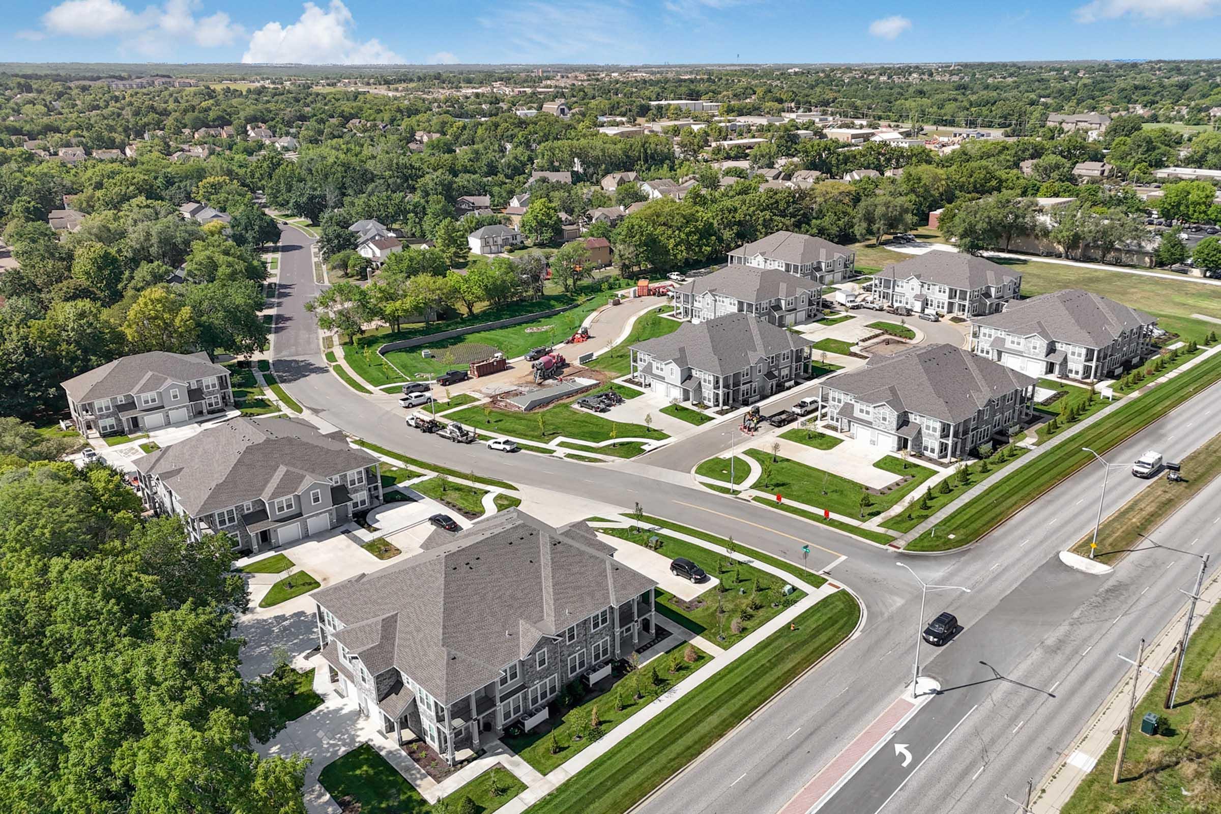Aerial view of a suburban neighborhood featuring well-maintained homes arranged in circular layouts with green lawns, mature trees, and quiet streets. Available parking spaces and smooth roadways are visible, emphasizing a peaceful residential community.