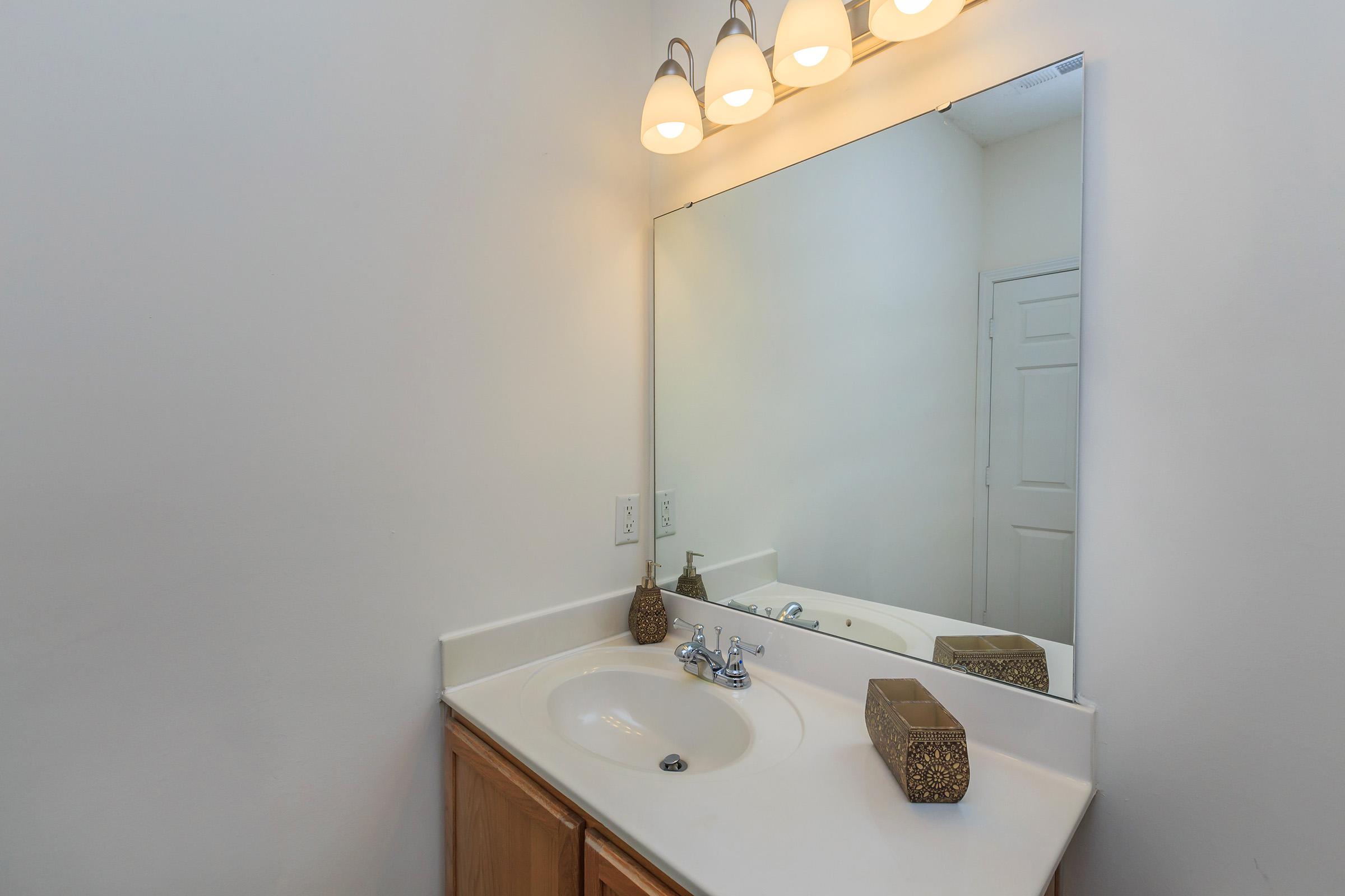 a white sink sitting under a mirror