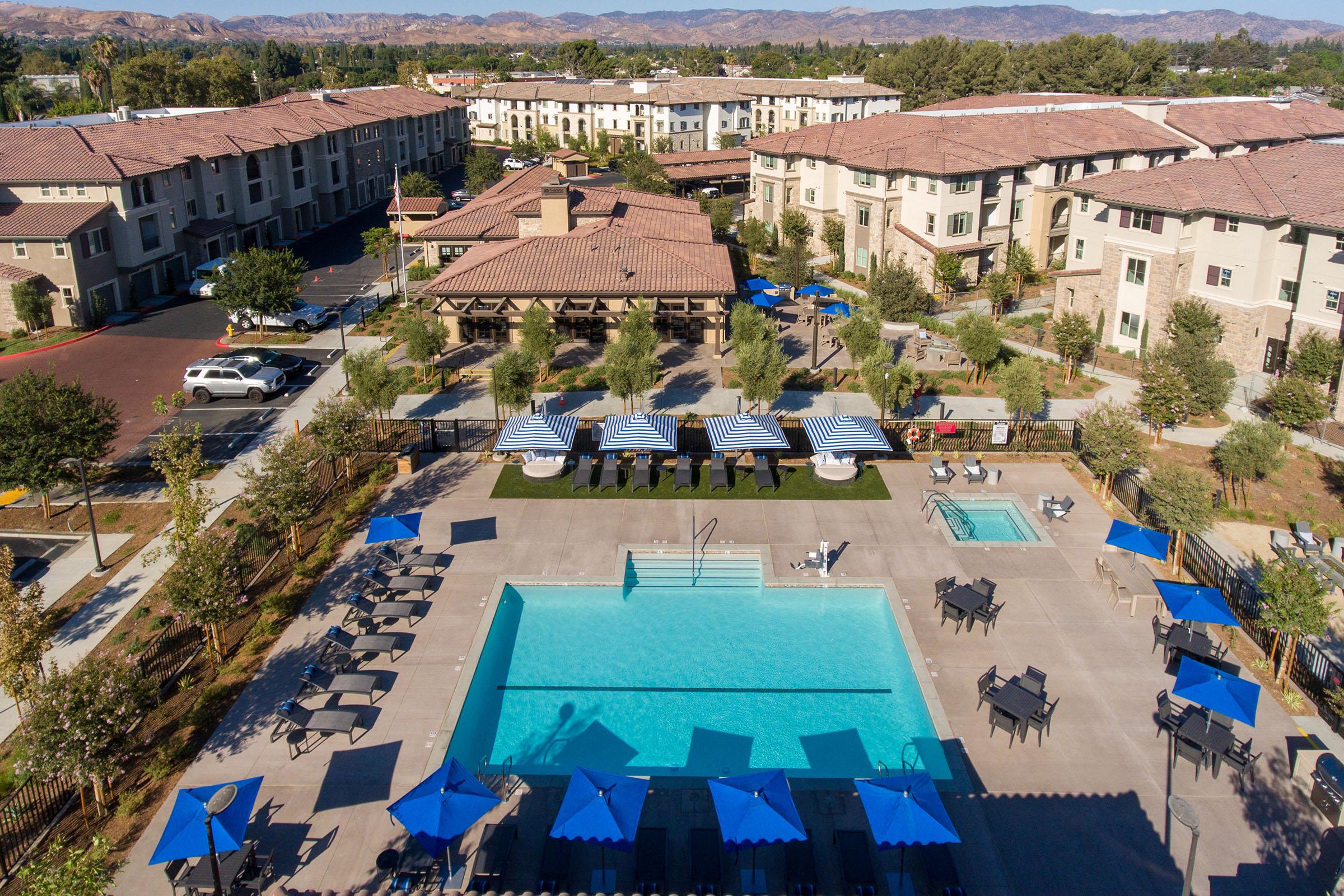 2-Bedroom Apartments In Simi Valley, CA - Landing At Arroyo - Shimmering Swimming Pool With A Hot Tub, Umbrellas, Tables, Chairs, Sofa Couch, And Grass Turf Area