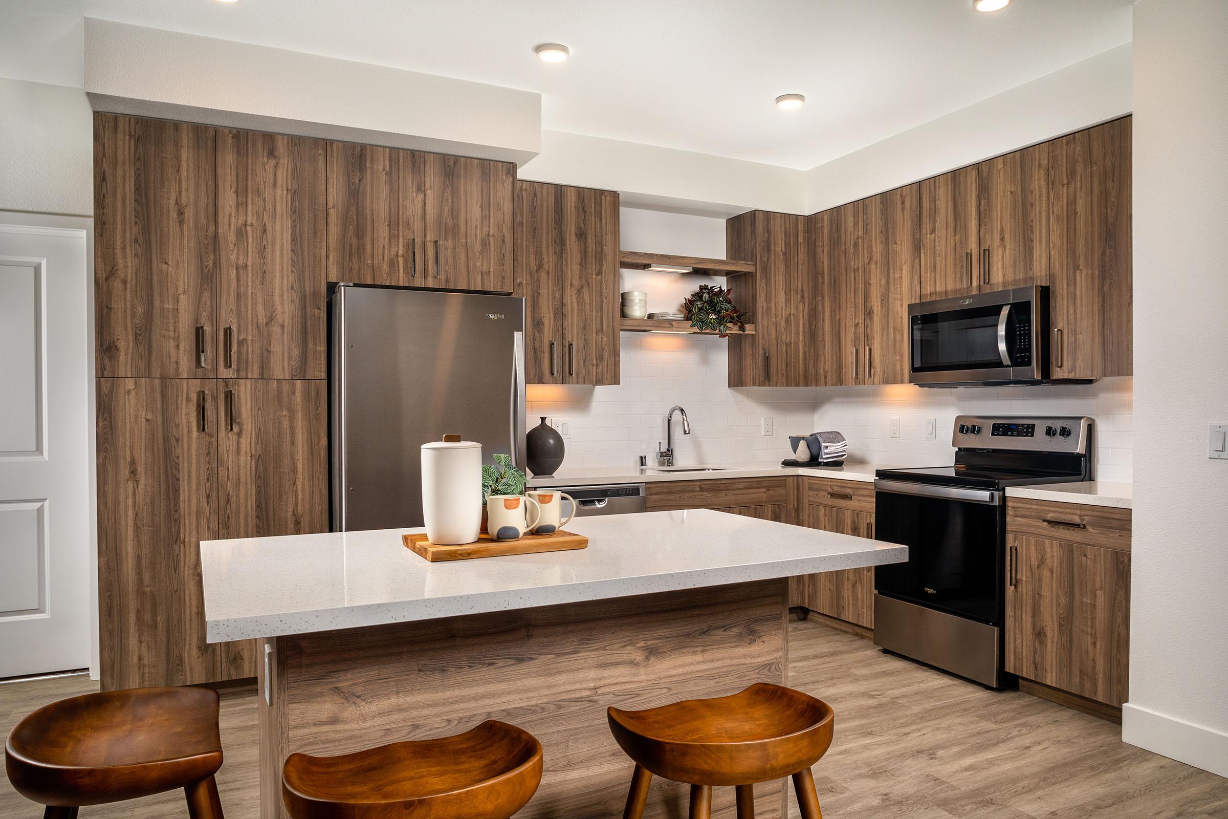 Apartments For Rent In Simi Valley, CA - The Landing At Arroyo - Wood-Inspired Kitchen With Stainless Steel Energy-Efficient Appliances, Vinyl Wood-like Flooring, Kitchen Island, And Hardwood Cabinets