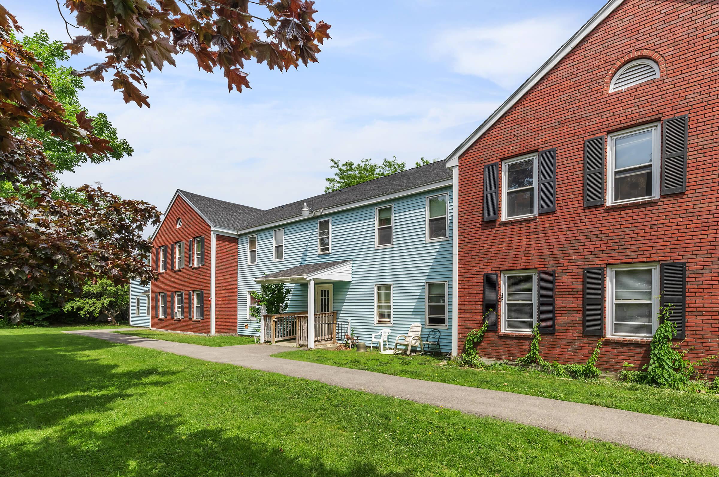 a large brick building with grass in front of a house