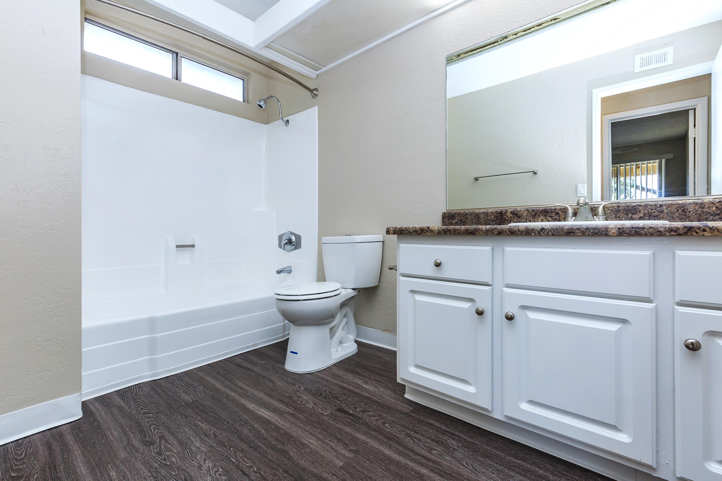 Vacant bathroom with white cabinets and wooden floors
