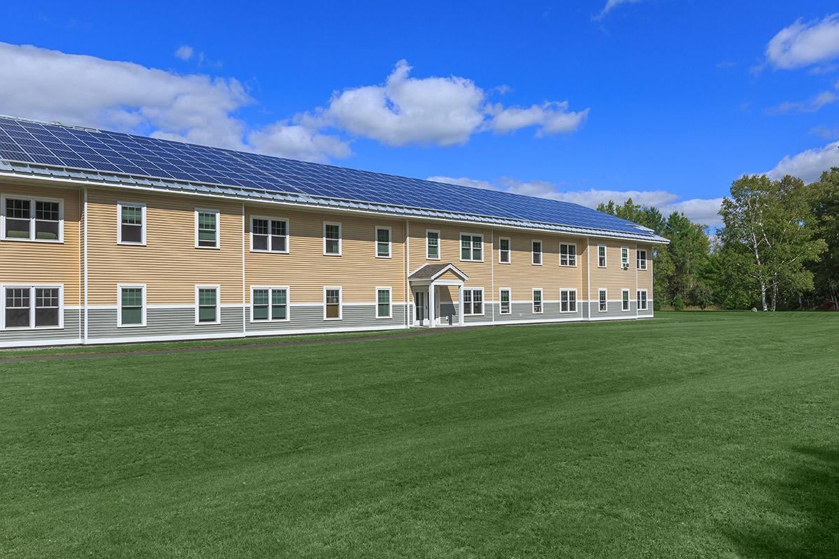 a large brick building with a grassy field