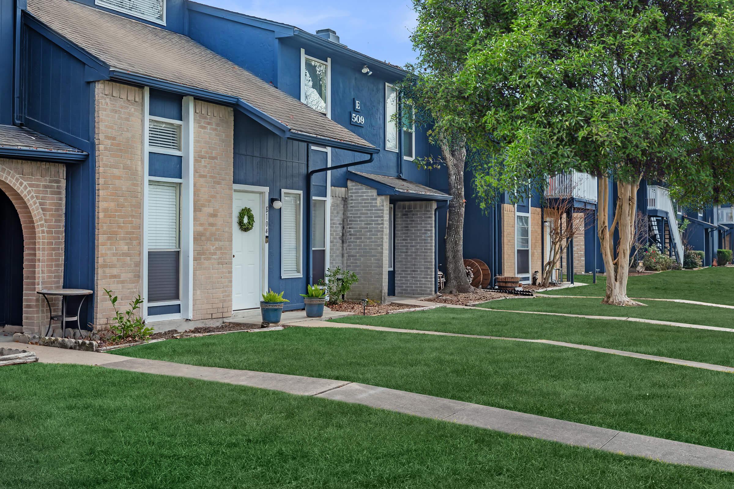 a large brick building with grass in front of a house