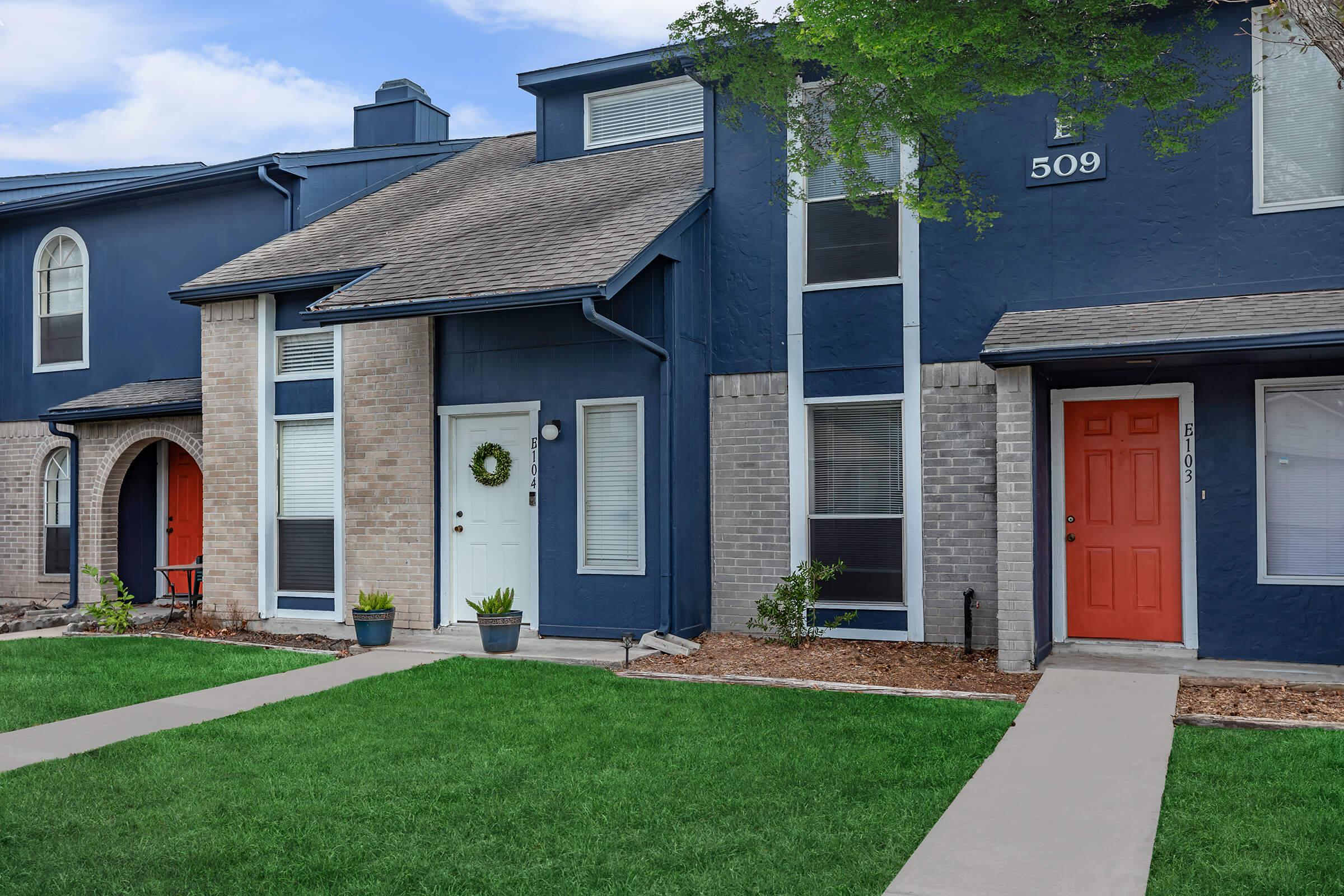 a house with a lawn in front of a brick building