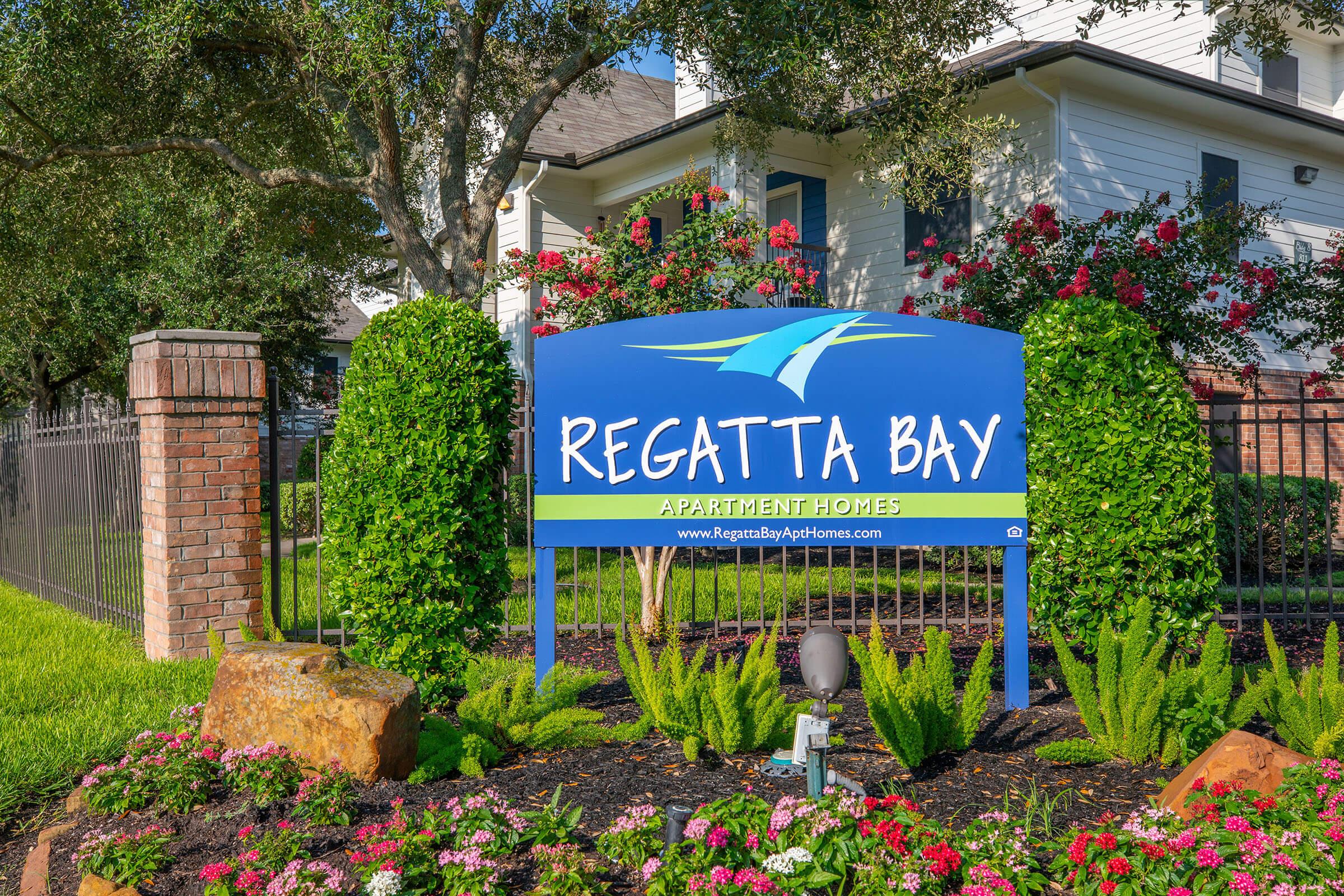 a sign on the side of a flower garden in front of a house