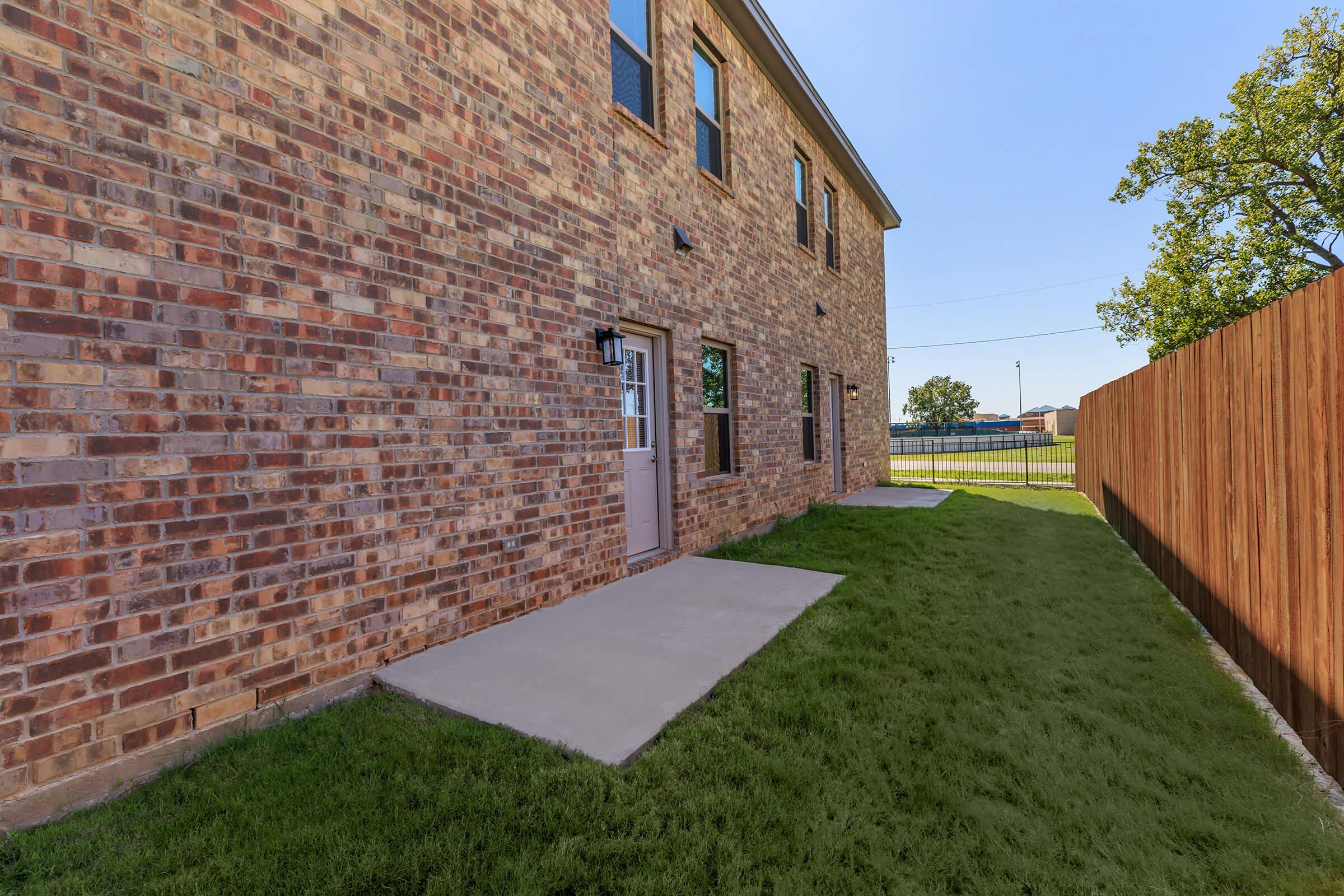 a large brick building with green grass