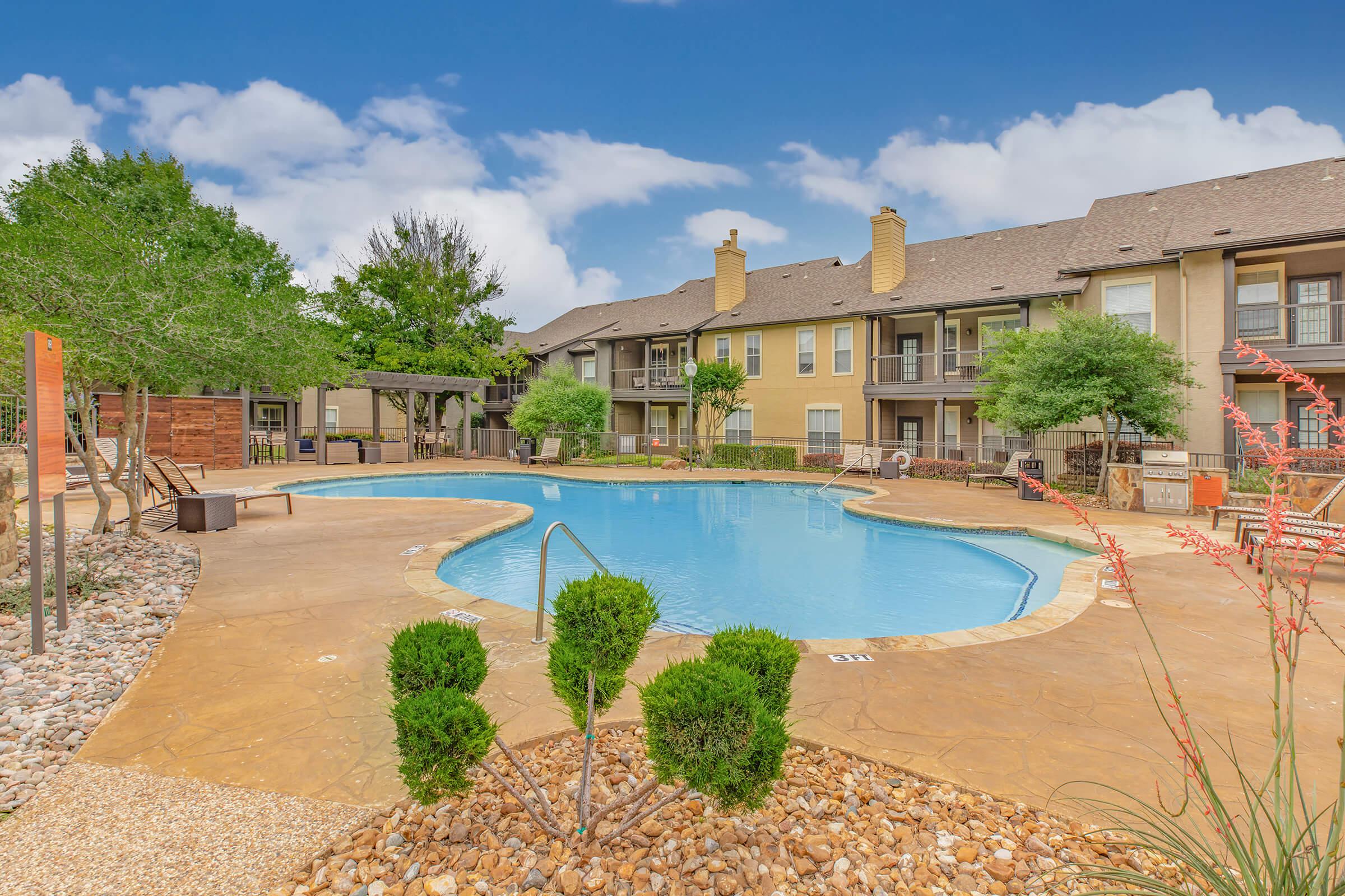 a community pool with green bushes