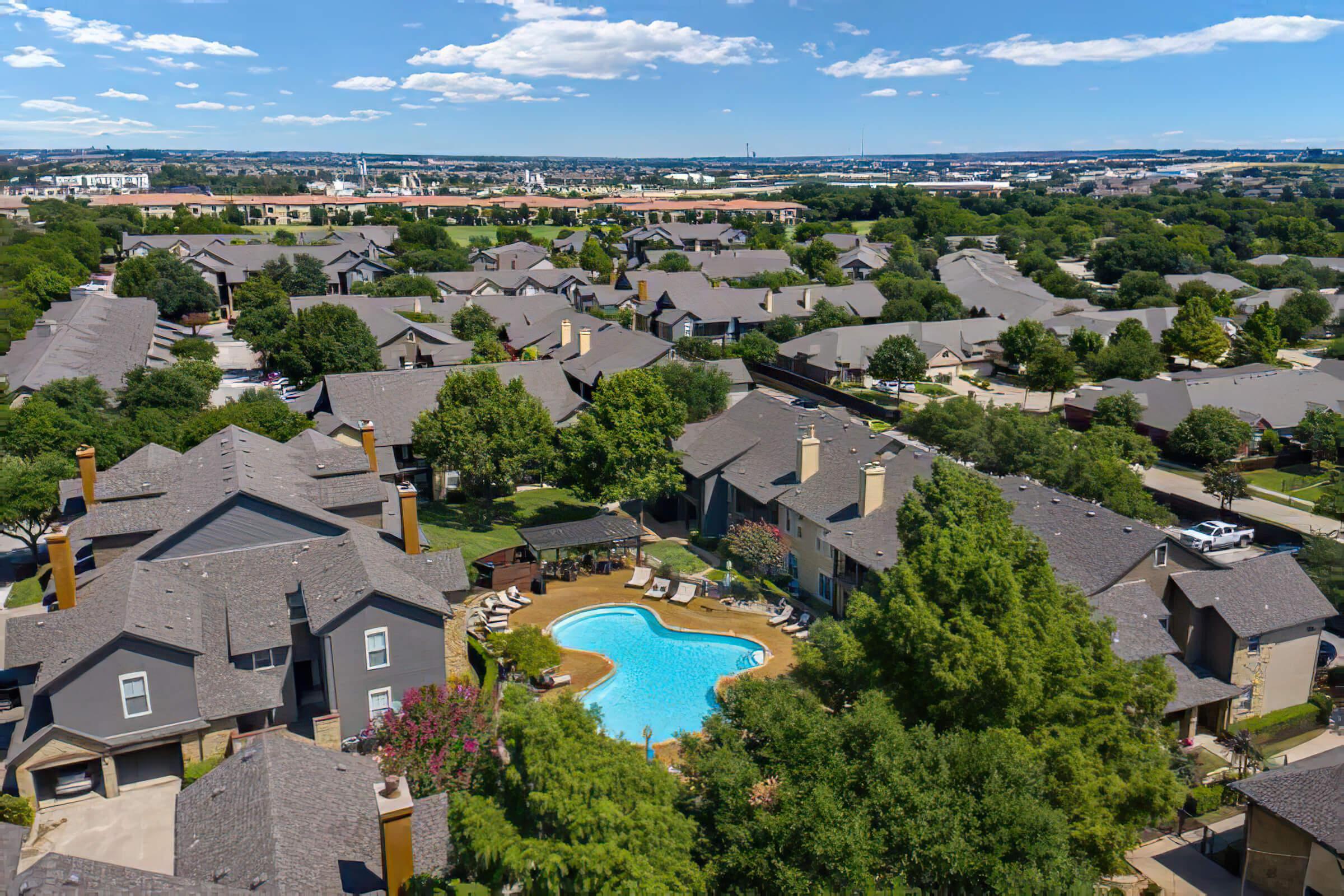 Aerial shot of the community building and pool with green trees