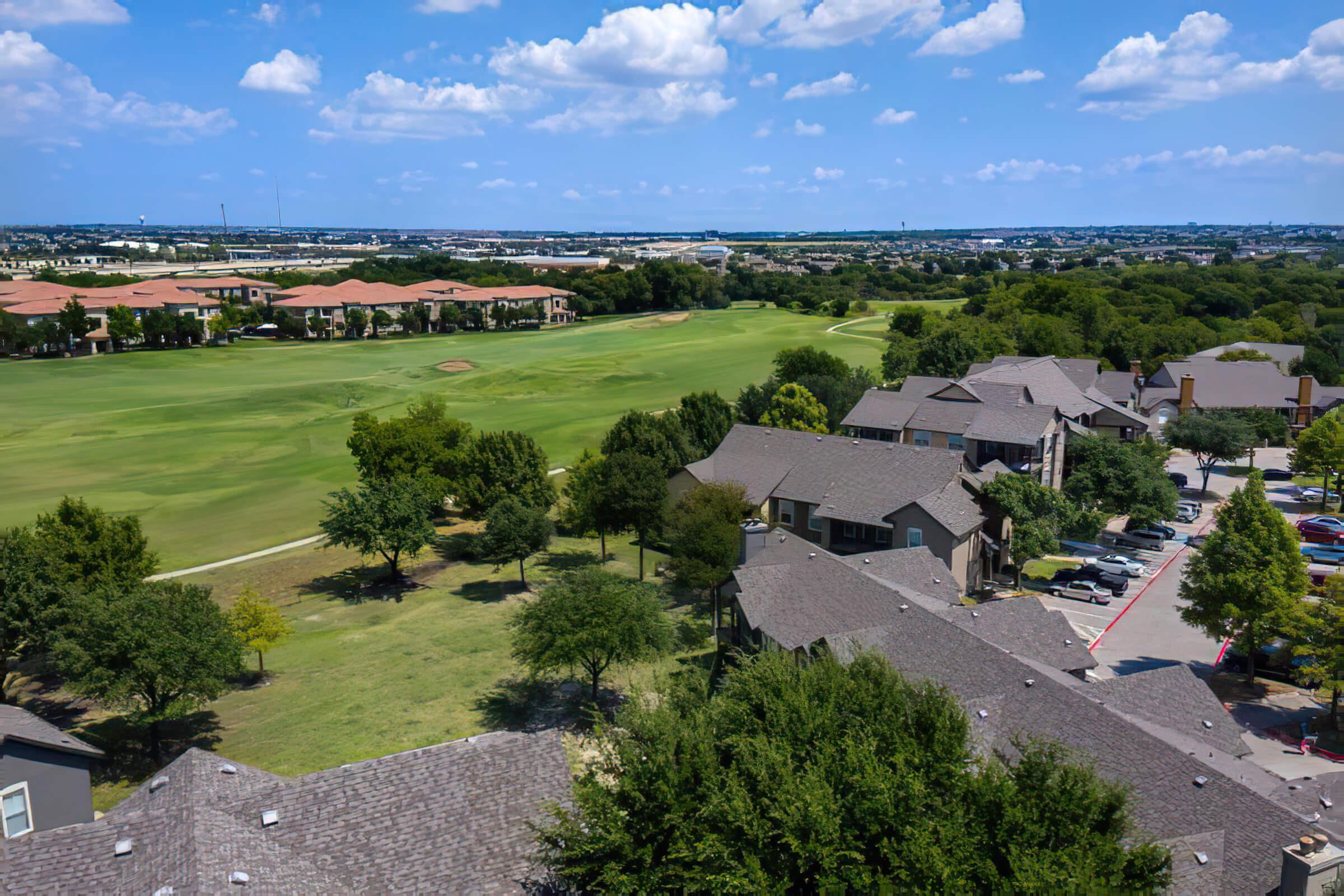 green trees and grass next to the community buildings