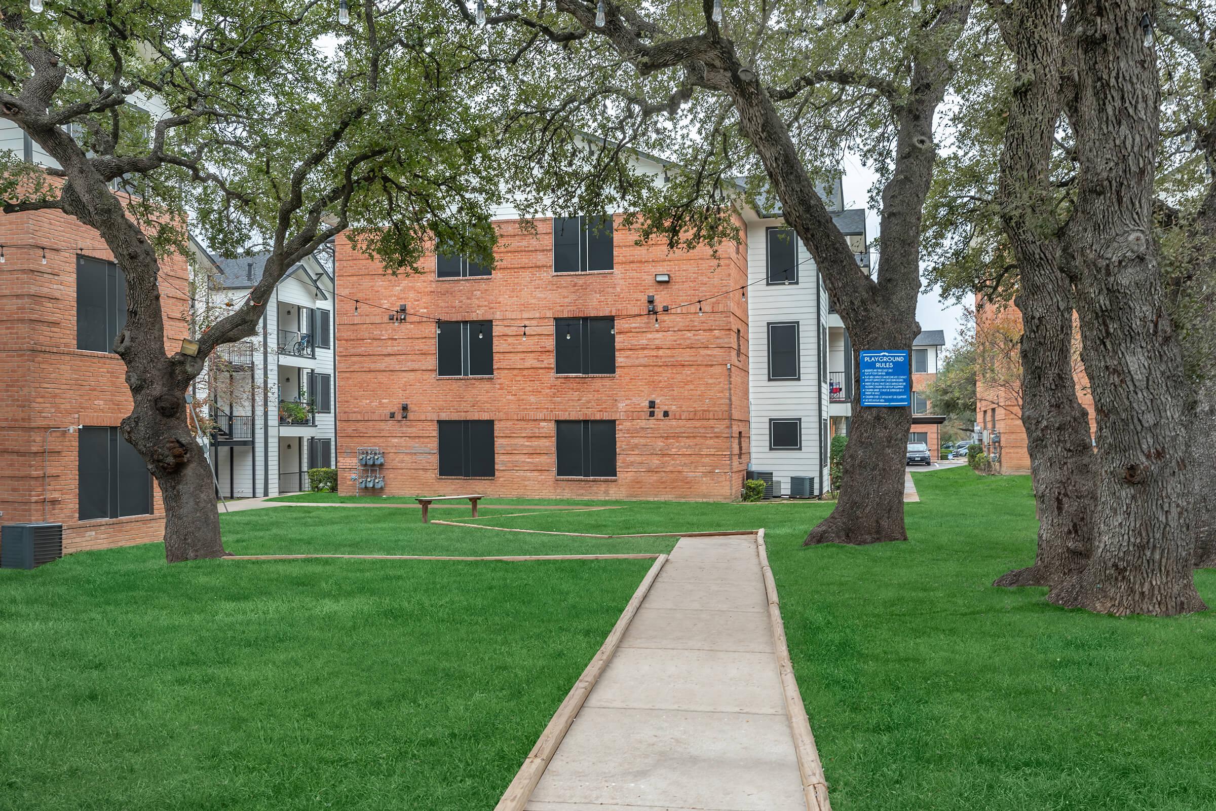 a large brick building with grass in front of a house