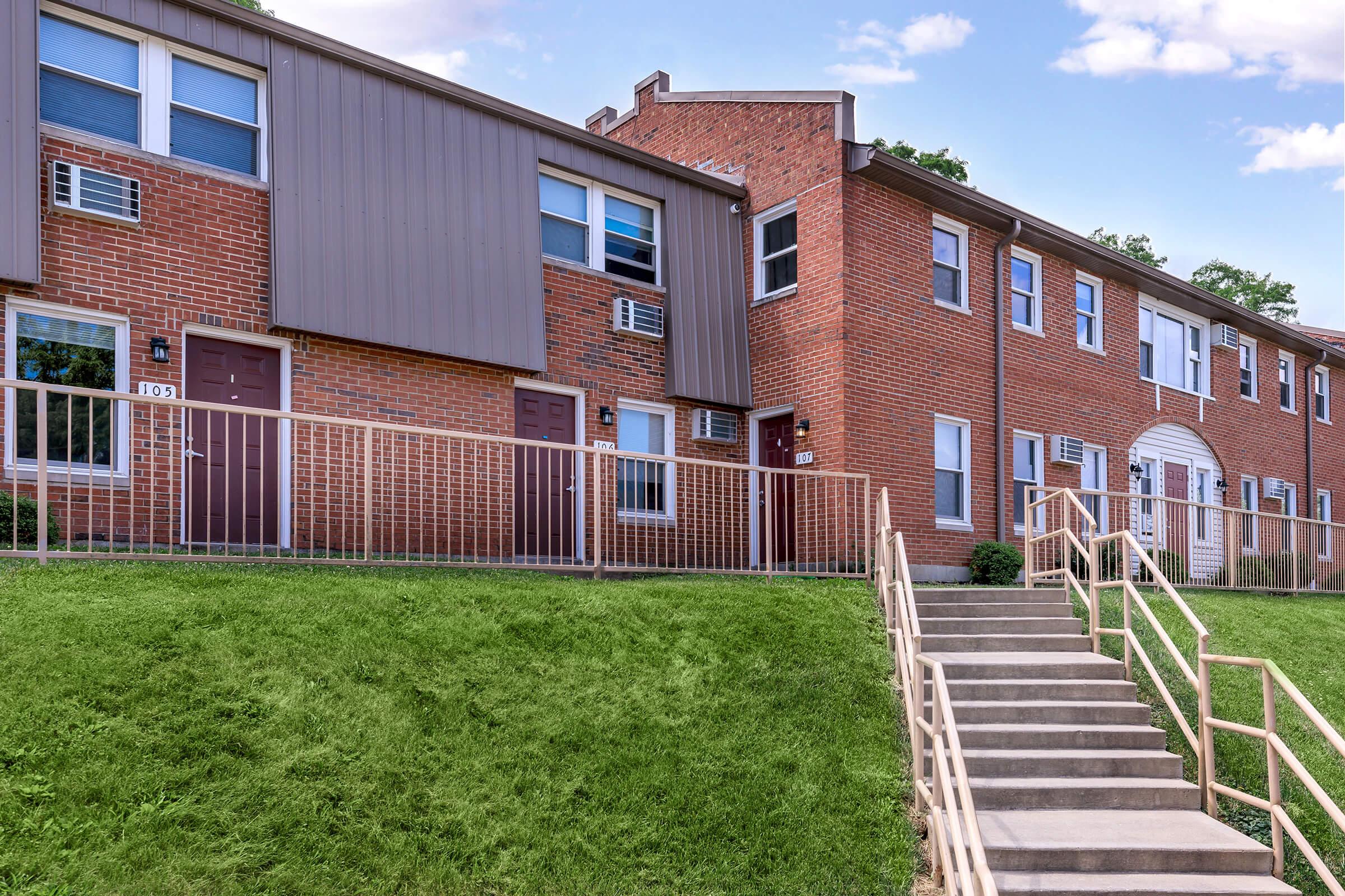 a large brick building with grass in front of a house