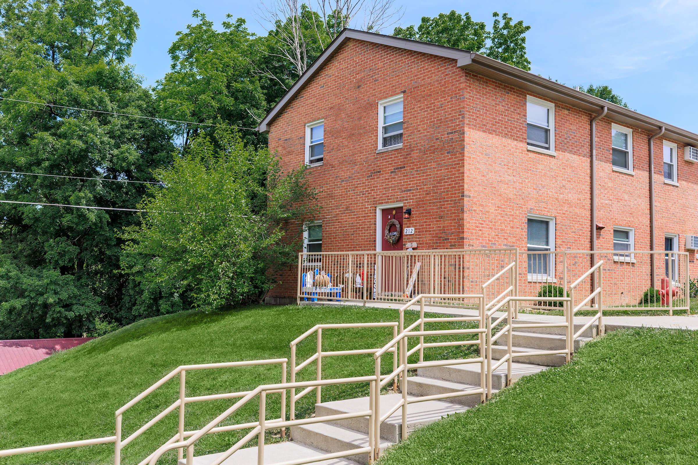 a house with a fence in front of a brick building