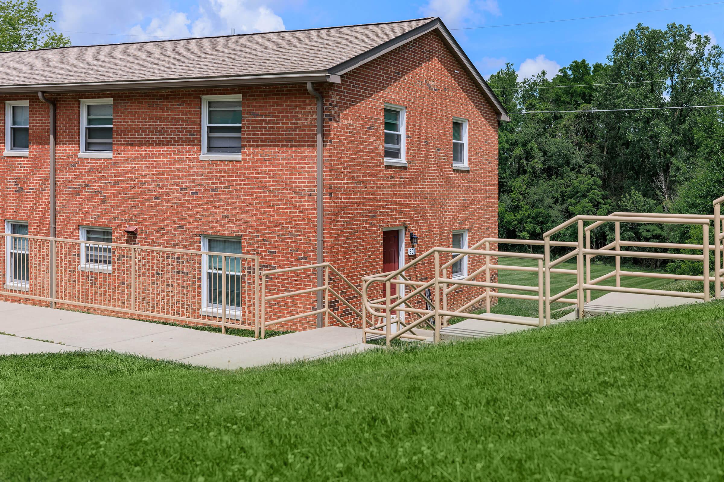 a large brick building with grass in front of a house