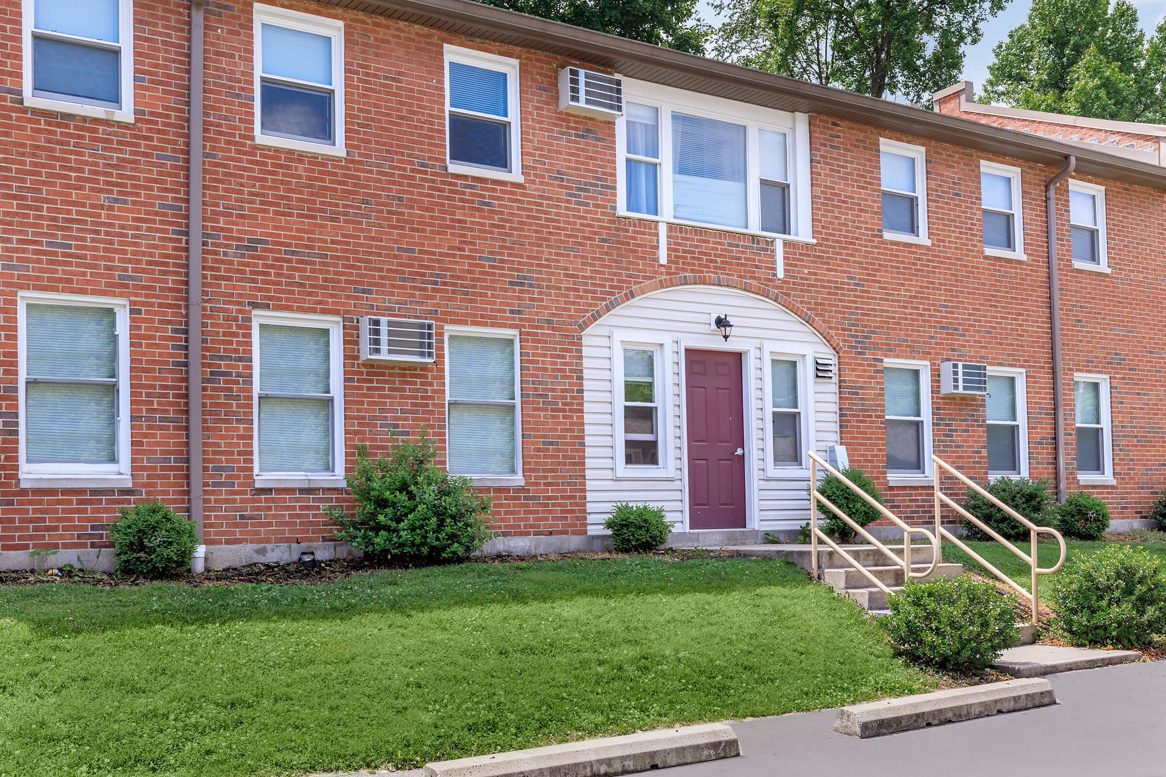 a large brick building with grass in front of a house