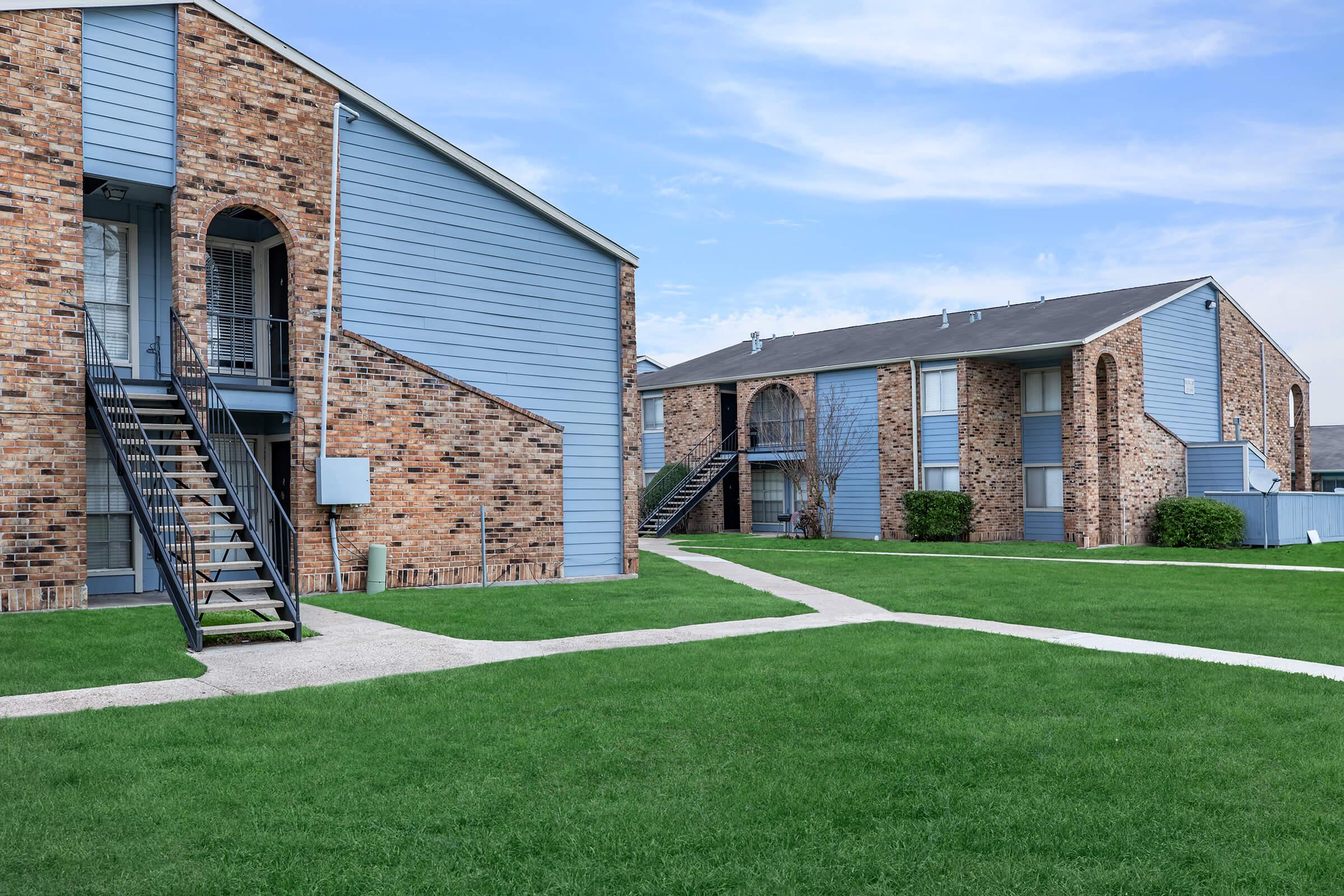 a large brick building with grass in front of a house with Bacon's Castle in the background