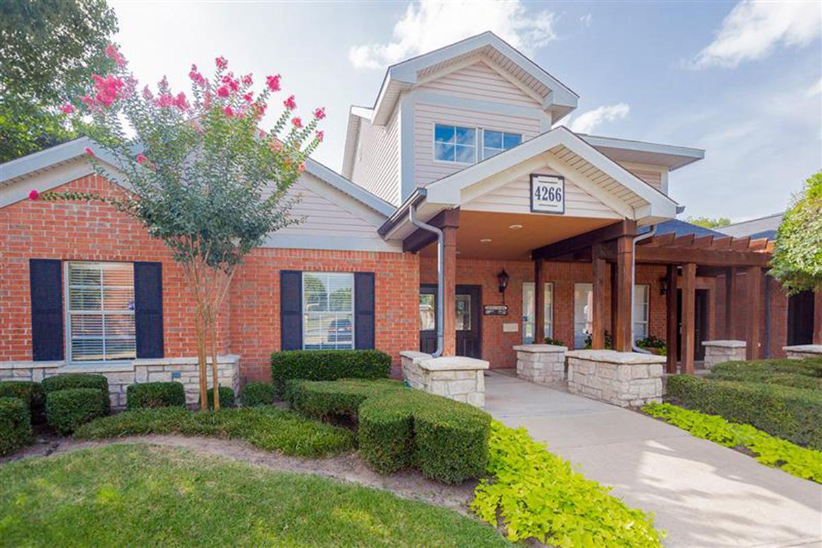 a large brick building with grass in front of a house