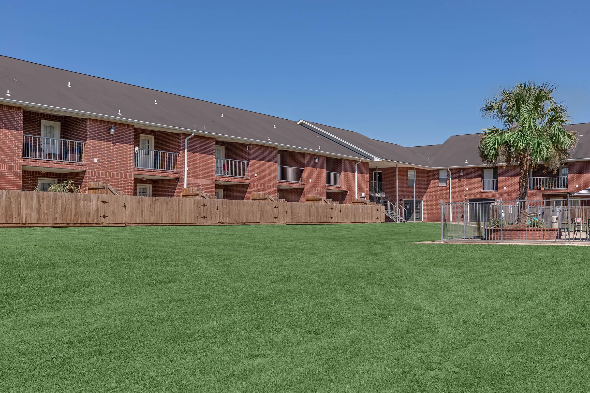 a large brick building with green grass