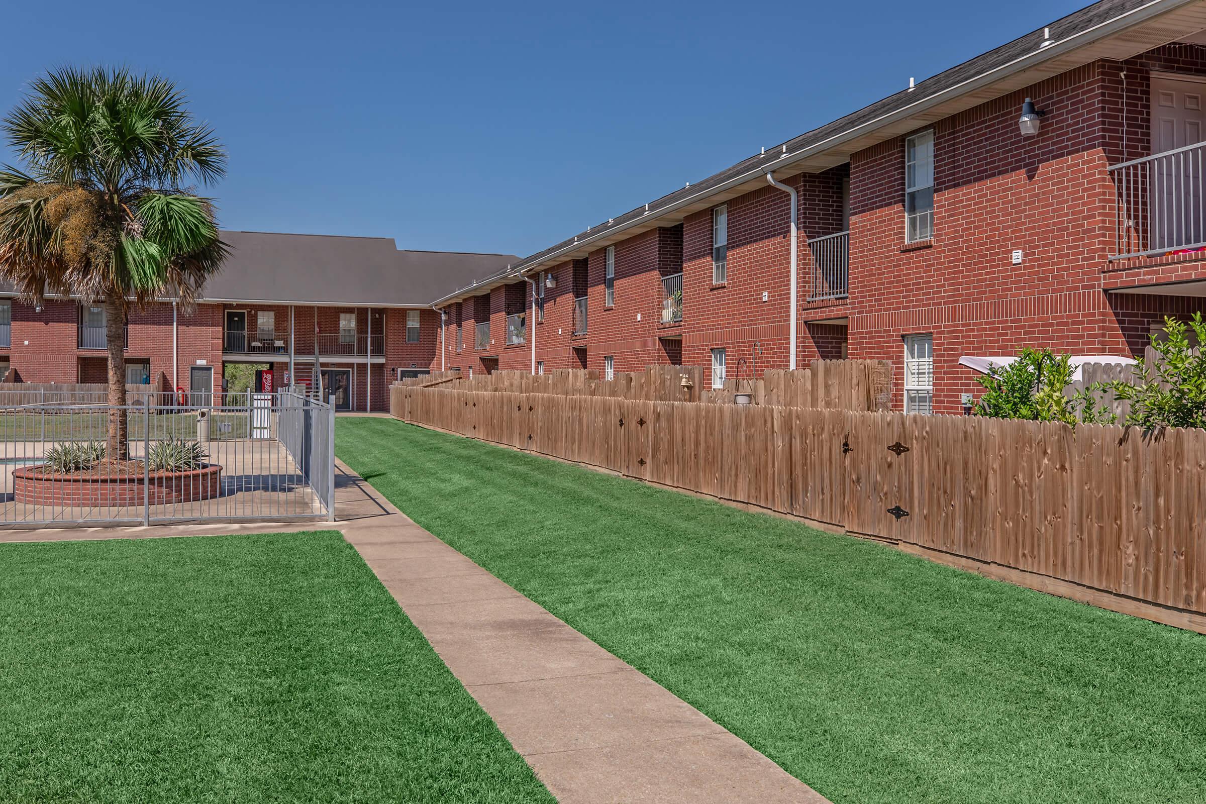 a large brick building with green grass with University of Louisiana at Lafayette in the background