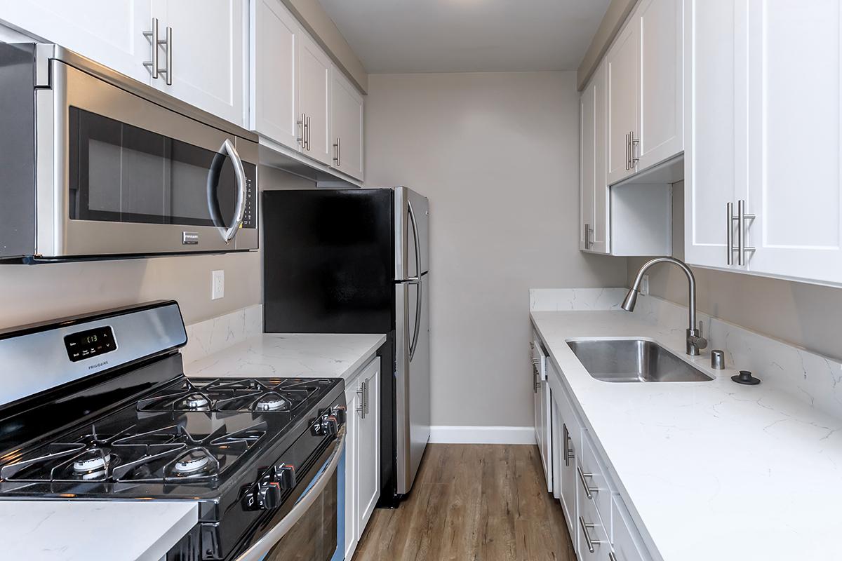 Galley kitchen with gas range and microwave above the stove along with a goose neck faucet at the sink in our one bed one bath C floor plan