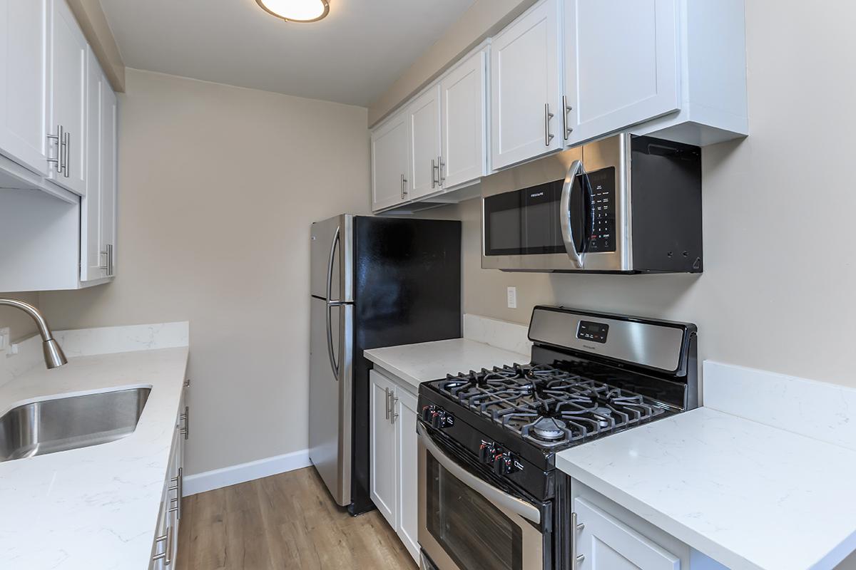 Stainless appliances also include an over the stove microwave at Flats on Elk. Notice the white cupboards and countertops along with the wood-like floors.