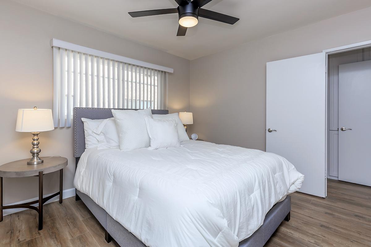 Roomy bedrooms here at Flats on Elk showcase ceiling fans, vertical blinds and wood-type flooring.