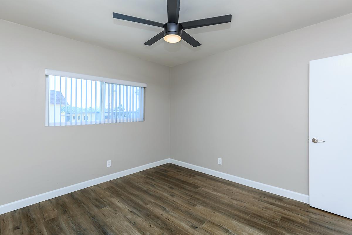 This bedroom photo showcases the black ceiling fan and wood like floors here at Flats on Elk.